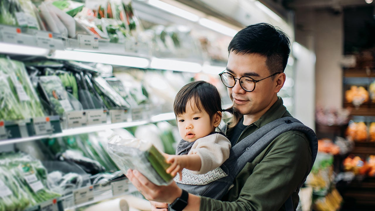 Young Asian father with cute little daughter grocery shopping for fresh organic vegetables in supermarket