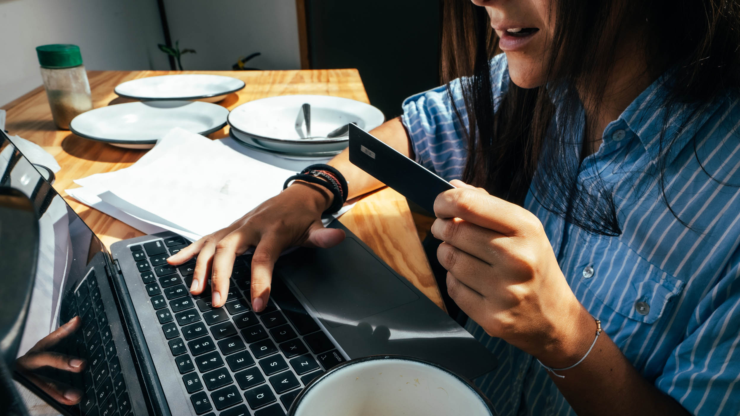 A woman types credit card information into a computer.