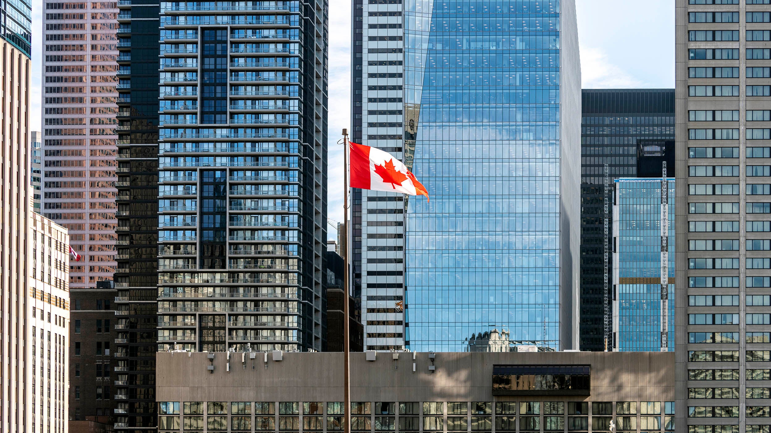 Canadian flag in front of modern skyscrapers