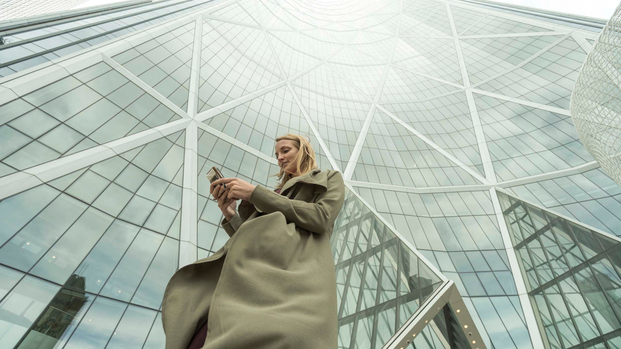 Woman looking at the phone outside the building