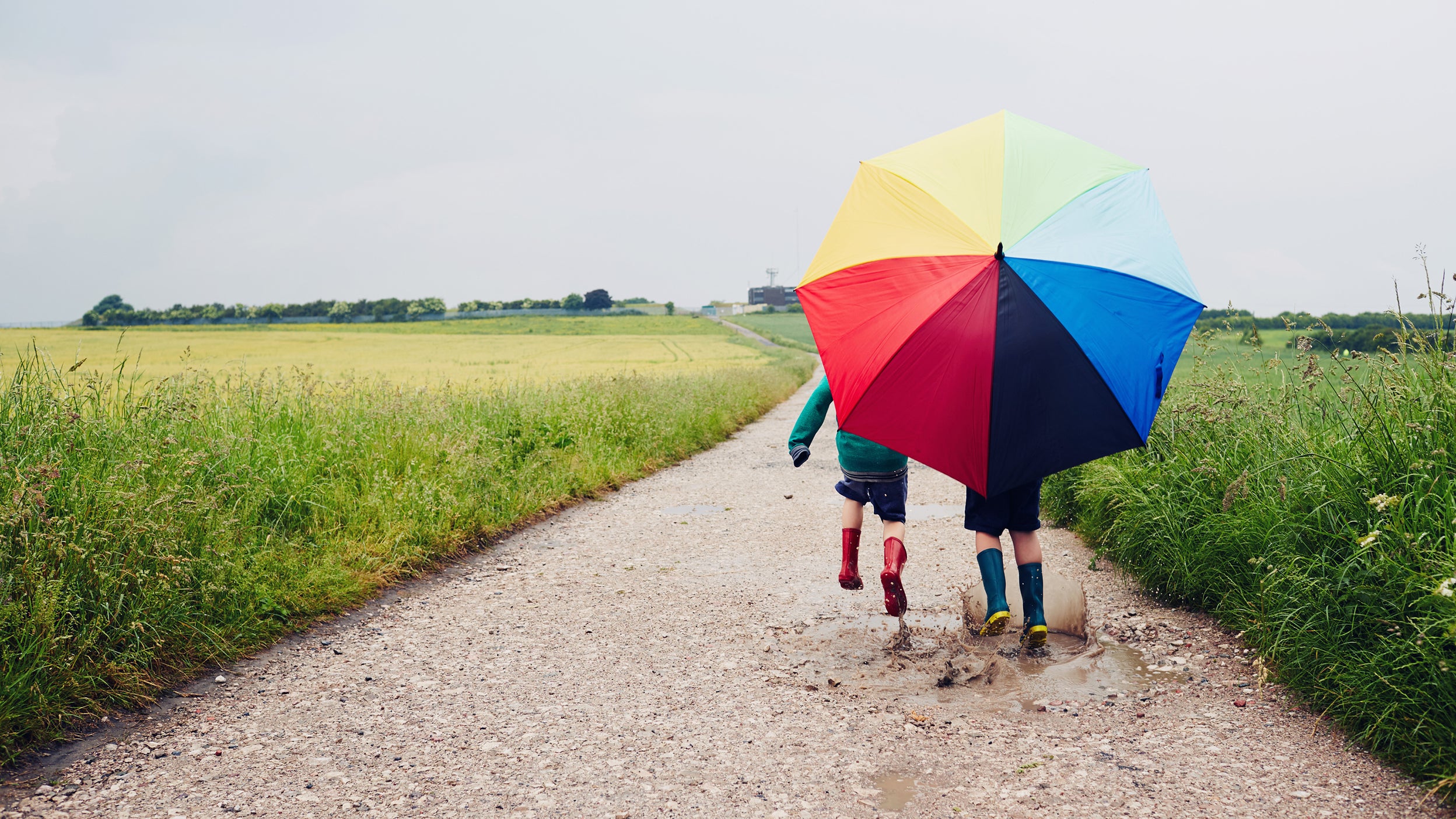 Children walking with a rainbow umbrella 