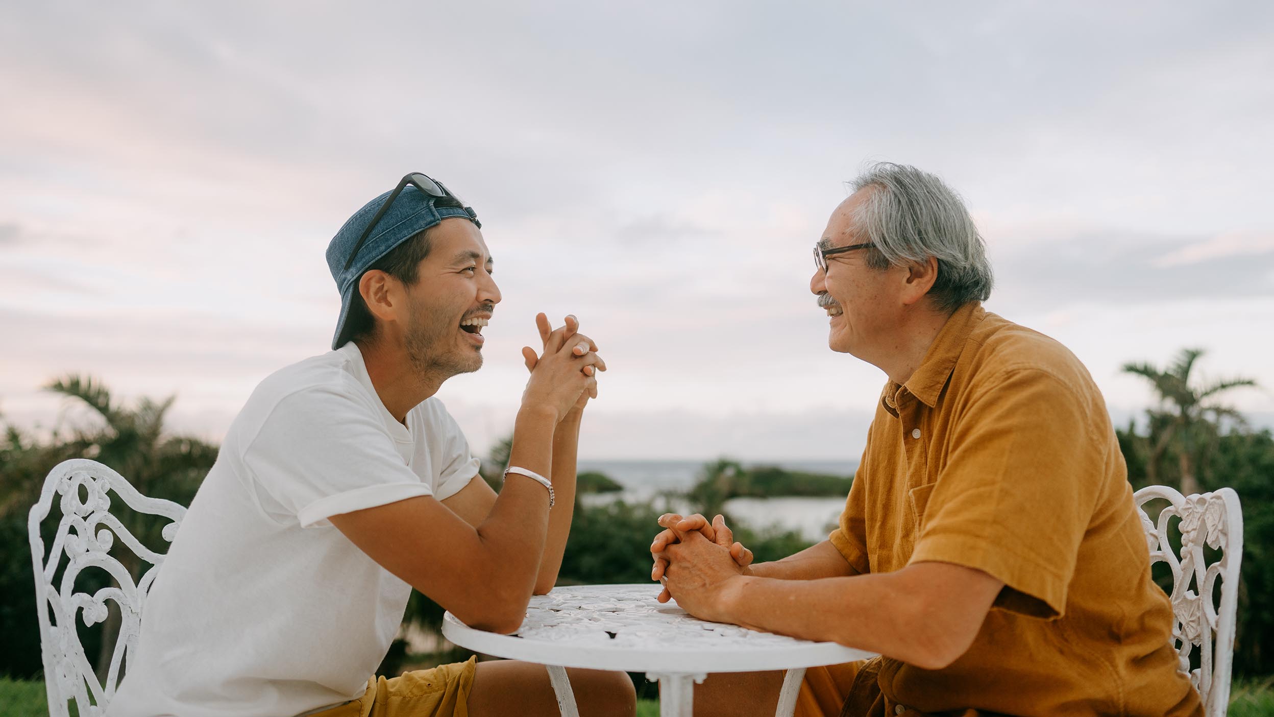 Père japonais senior et fils adulte discutant sur la terrasse