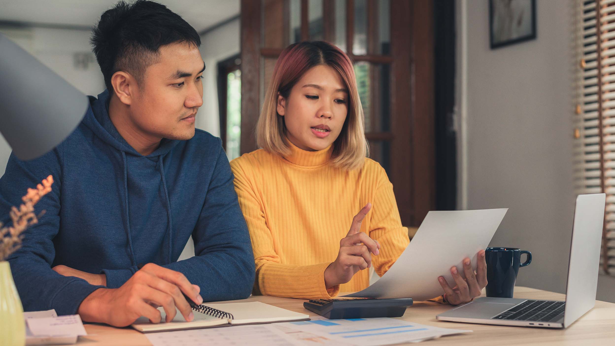 Woman and man doing paperwork together, paying taxes online on notebook pc