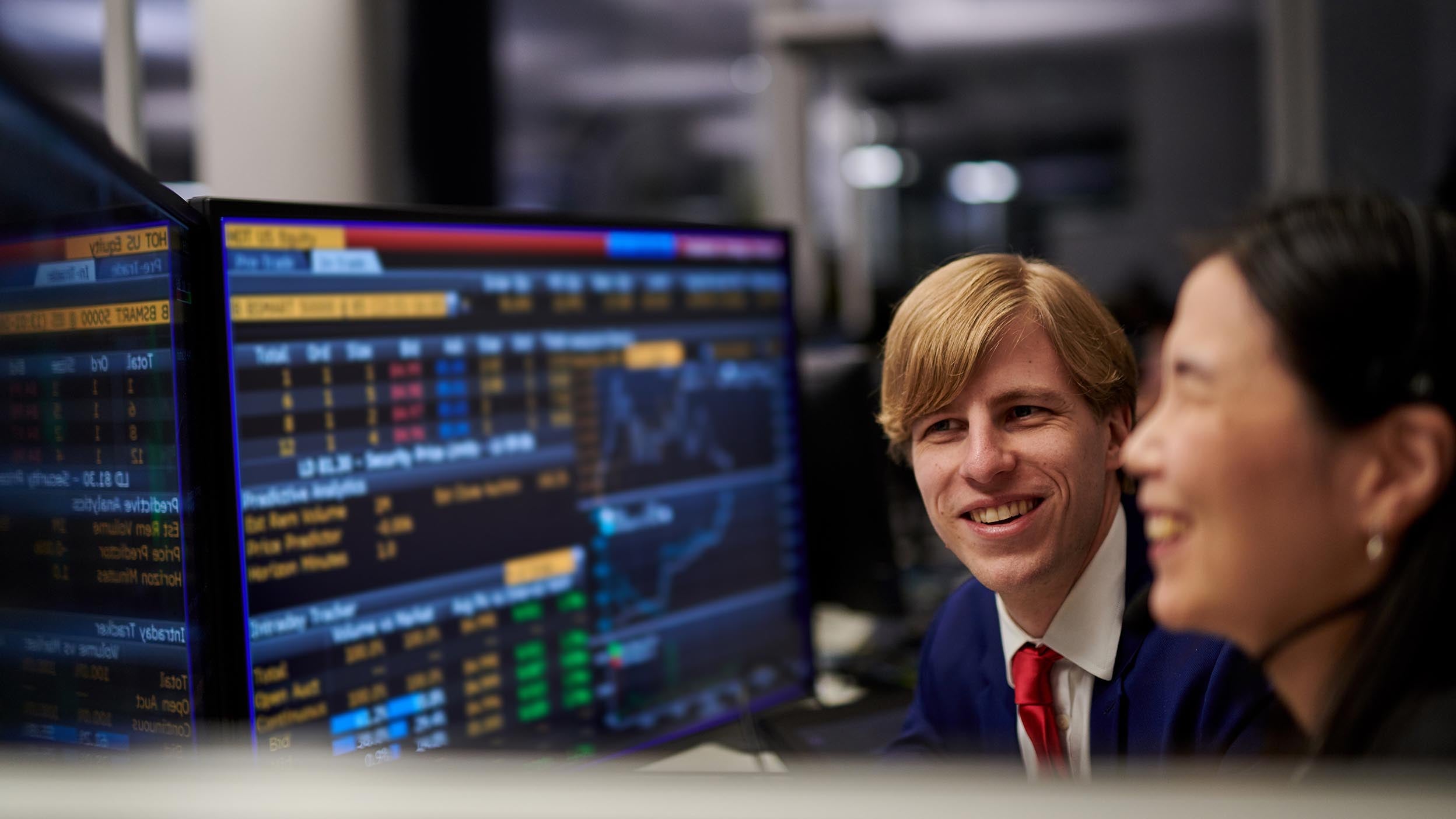 Man and woman looking at the monitor with stock market data