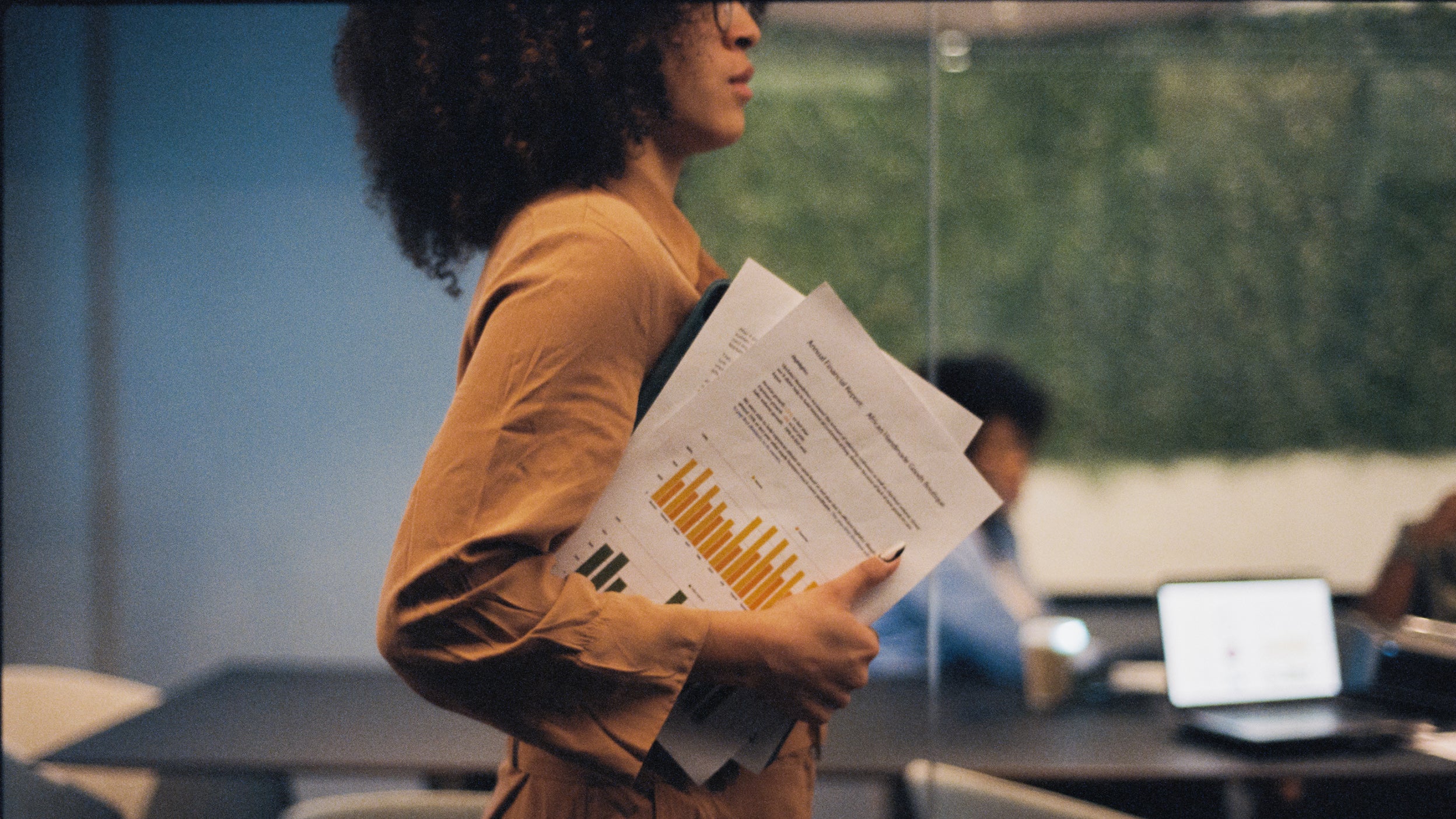 Person walking through an office holding a report with colorful charts.