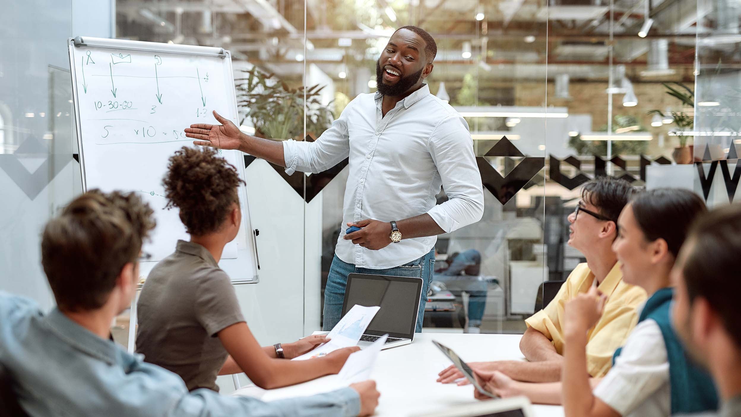 Man explaining something on whiteboard to his colleagues