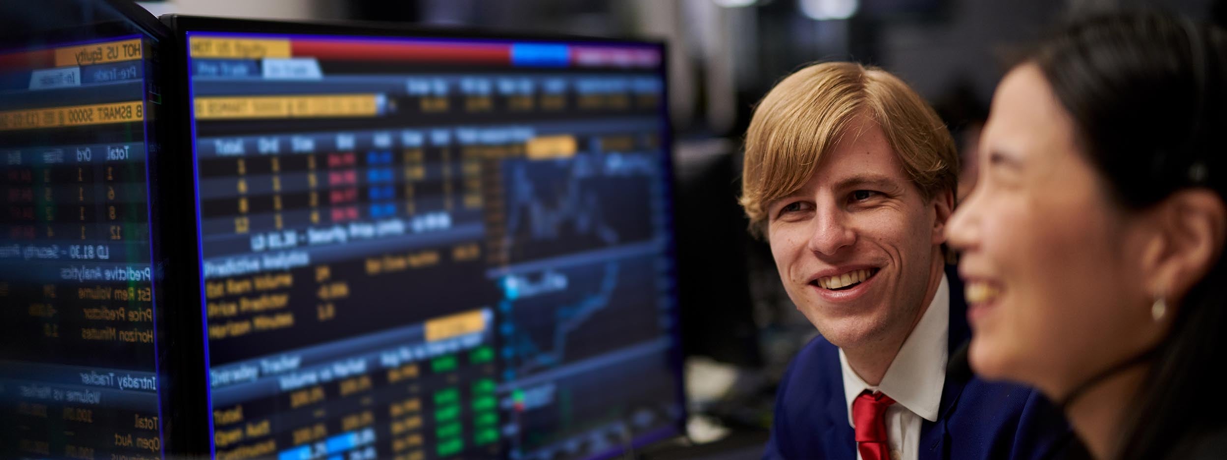 Man and woman looking at the monitor with stock market data