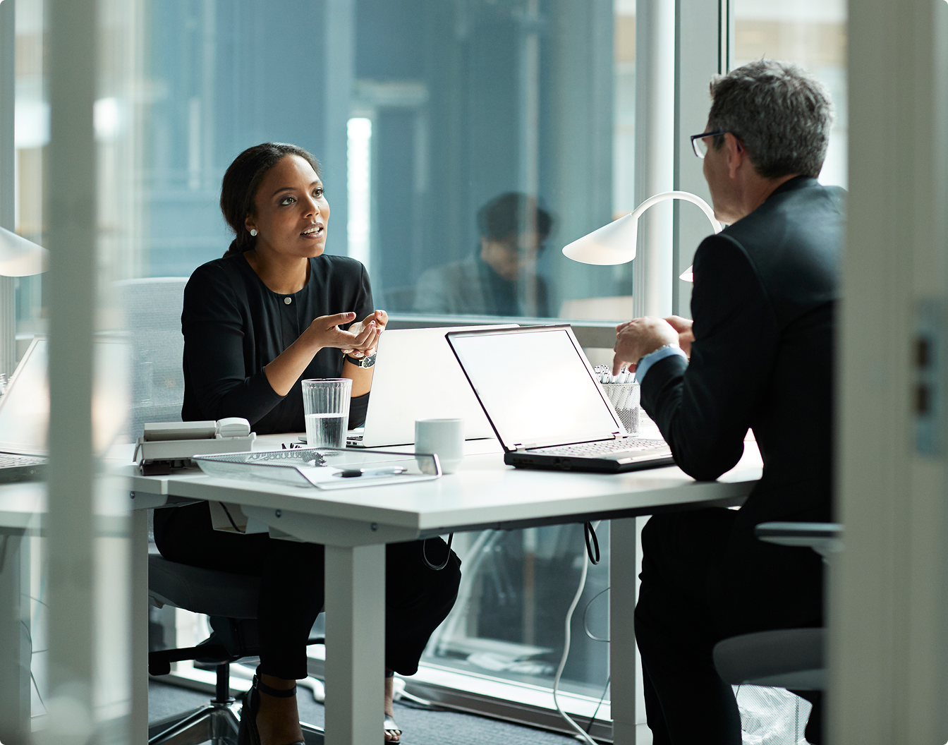 Two people talking in front of laptop