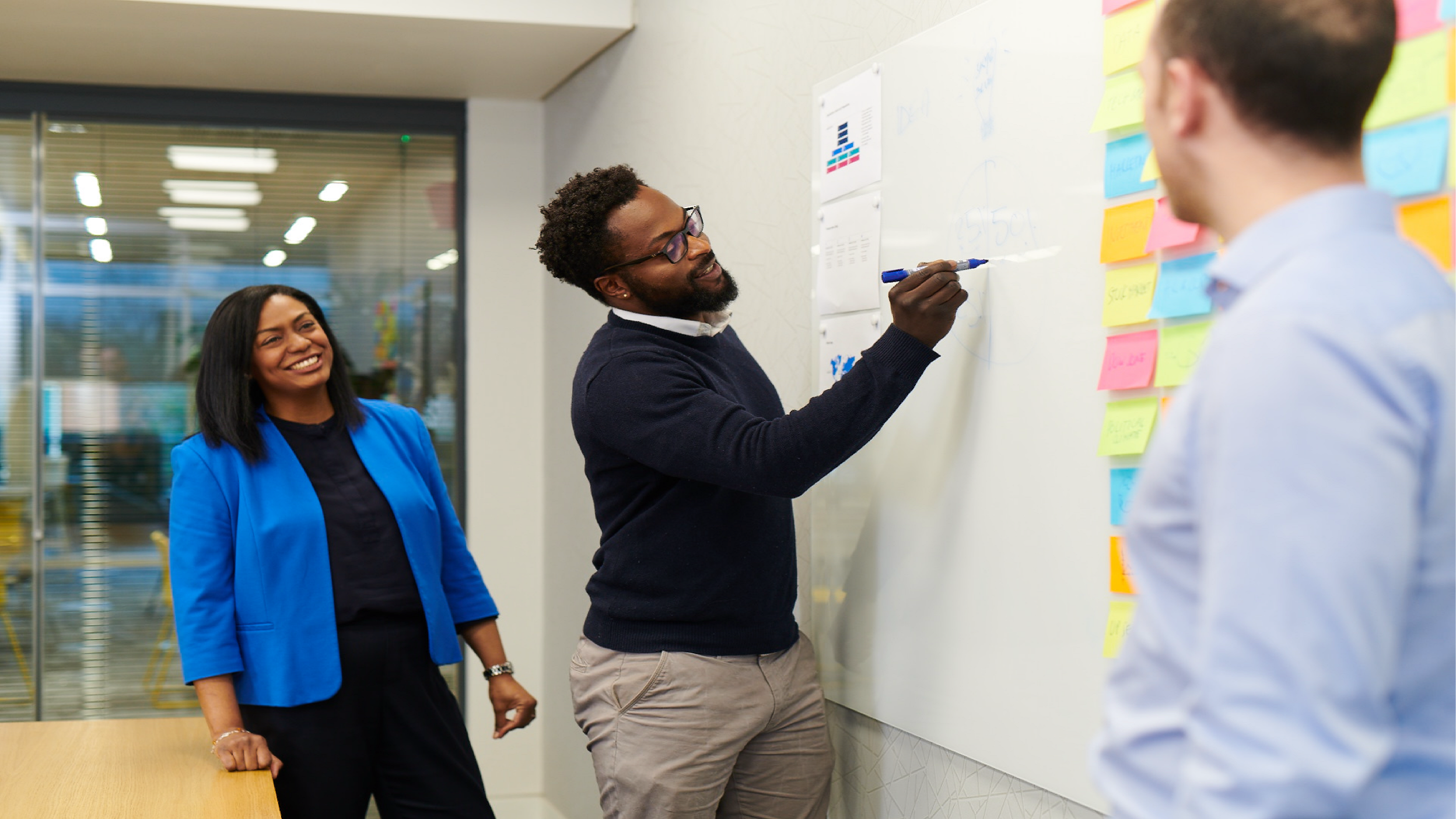 Employee writing on board during brainstorm