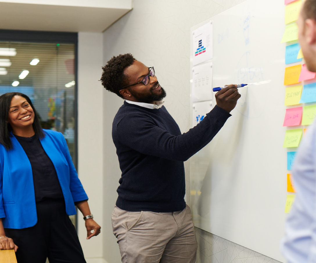 Employee writing on board during brainstorm