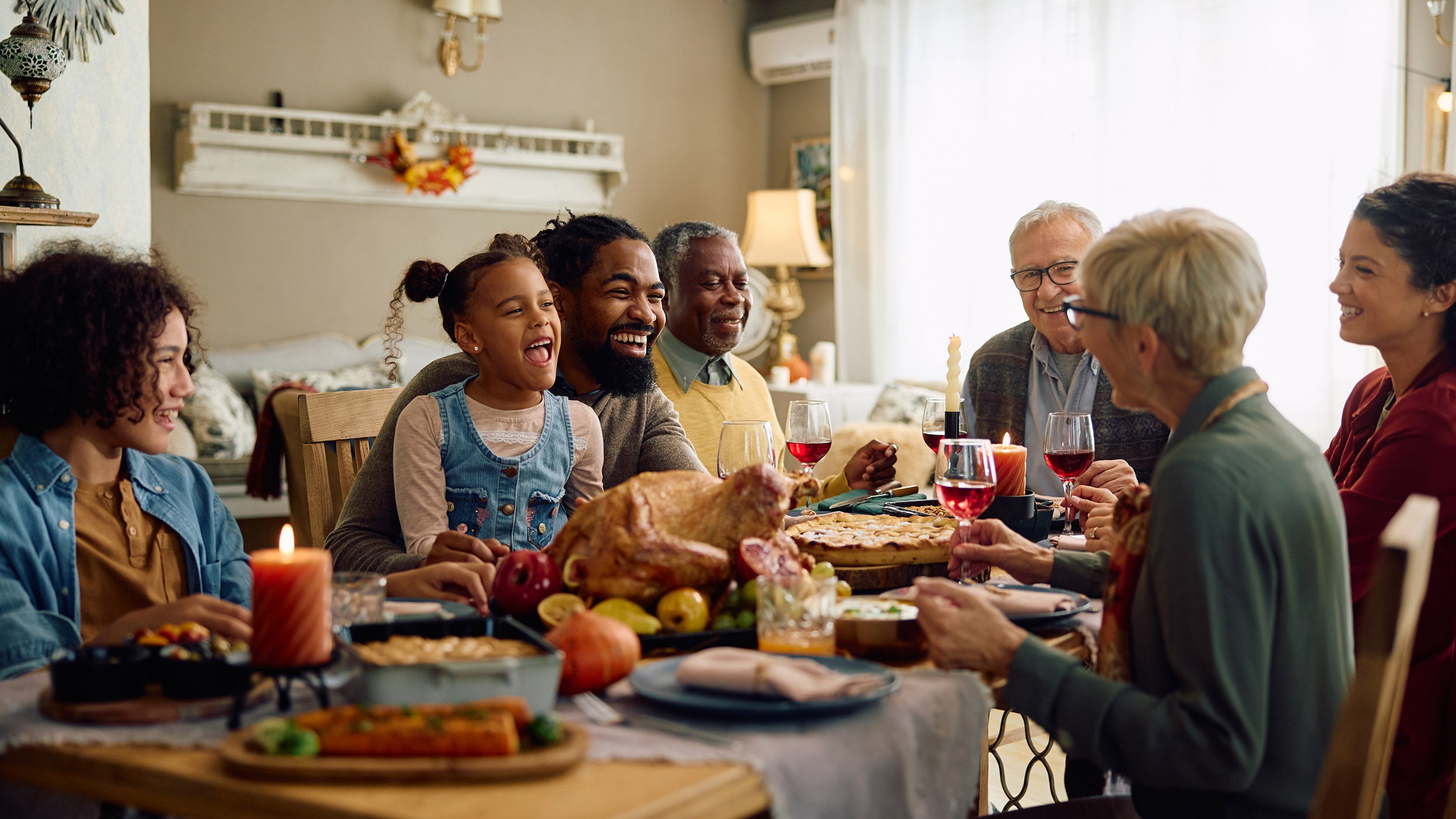 Happy extended family having fun while gathering at dining table on Thanksgiving.