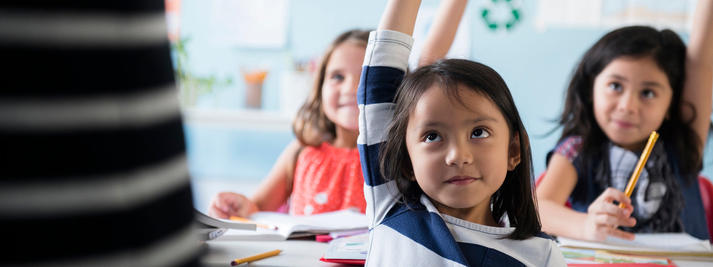 kids raising their hand up in the class