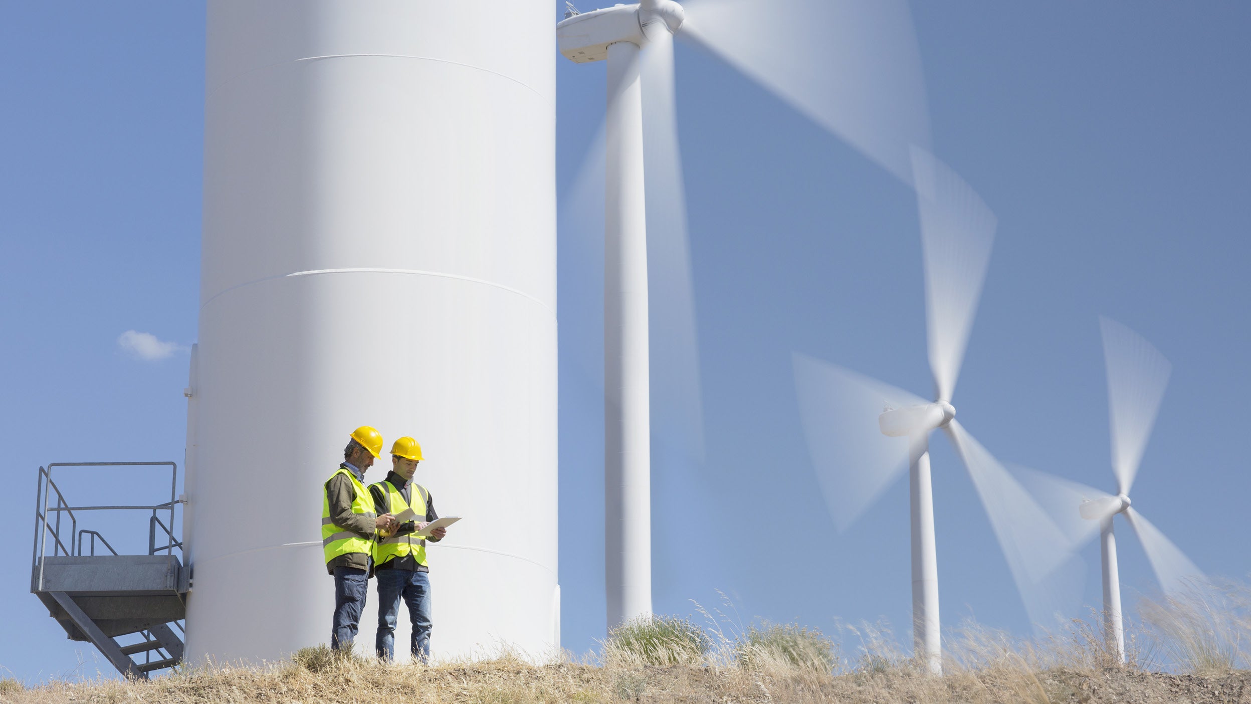 Due uomini in piedi davanti alle turbine eoliche