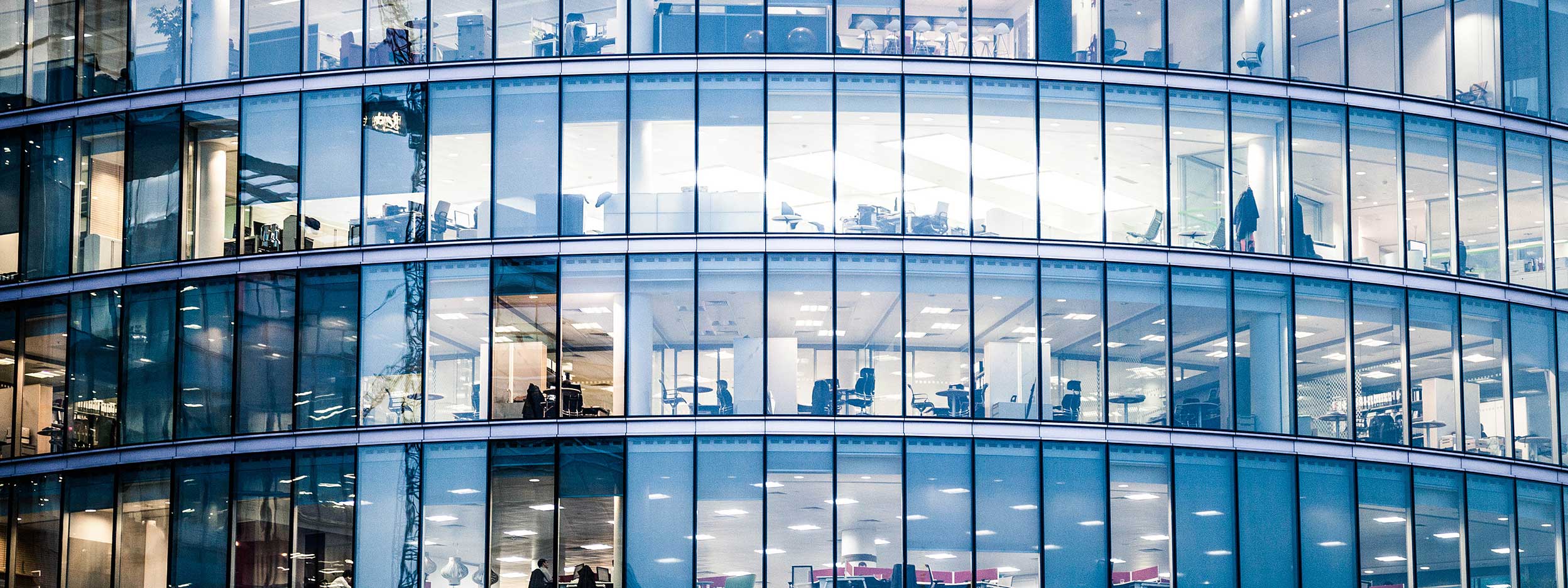 Modern glass office building with illuminated workspaces