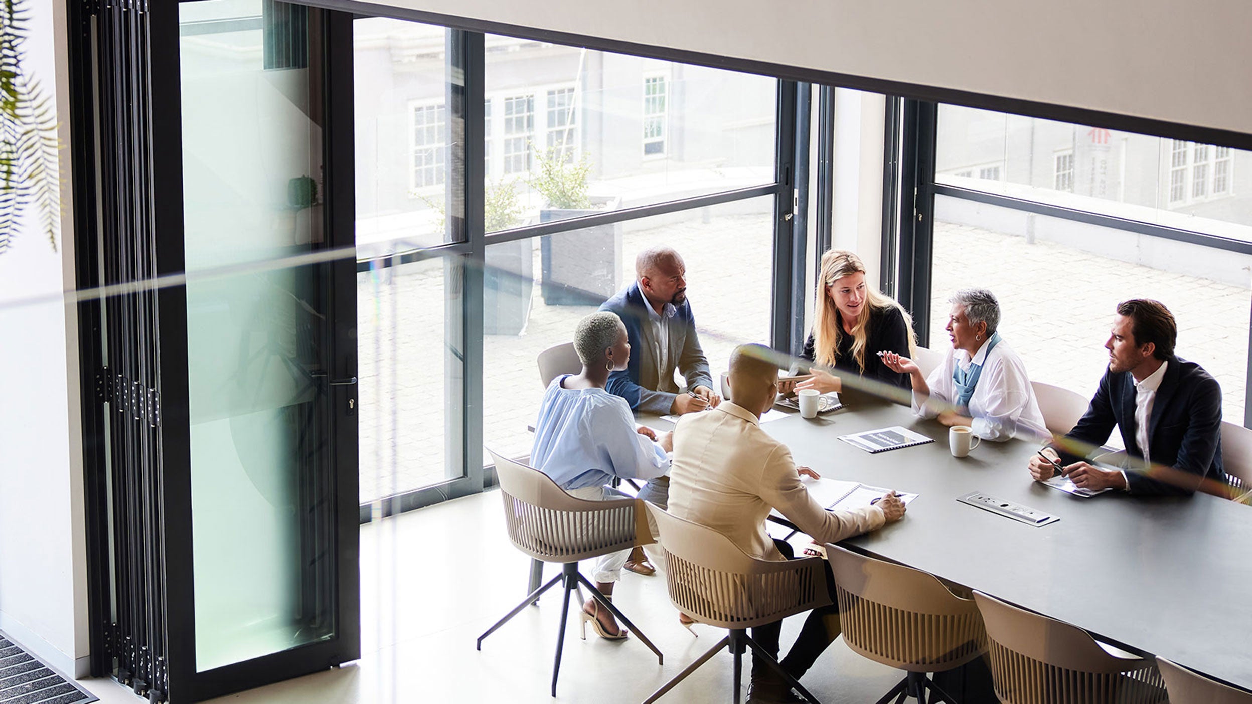 High angle view of a diverse group of businesspeople talking together around a conference table during a boardroom meeting in an office.