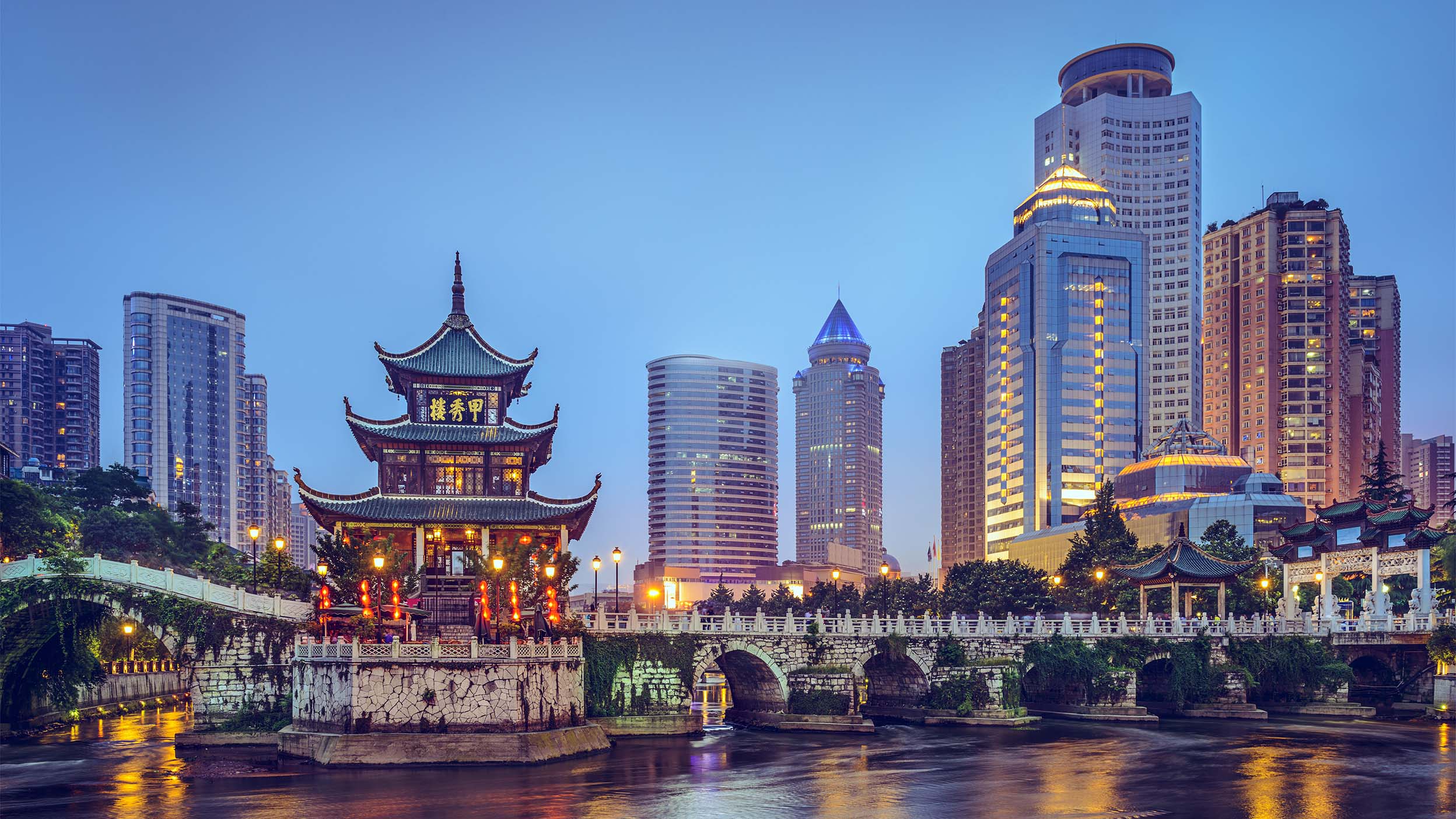 Old white bridge with traditional Asian house with modern buildings in background