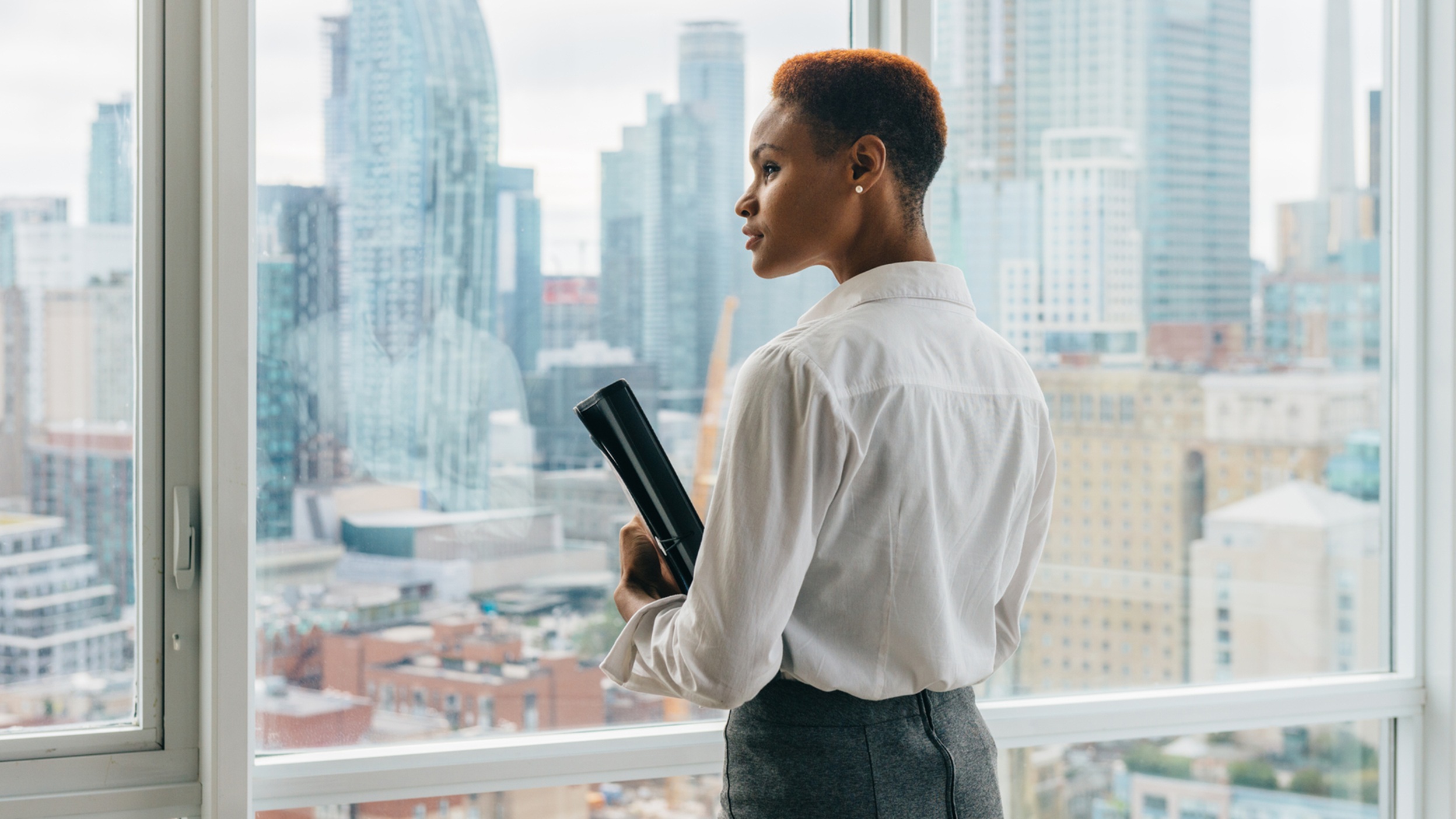 Business professional looking out over a city skyline from an office window.