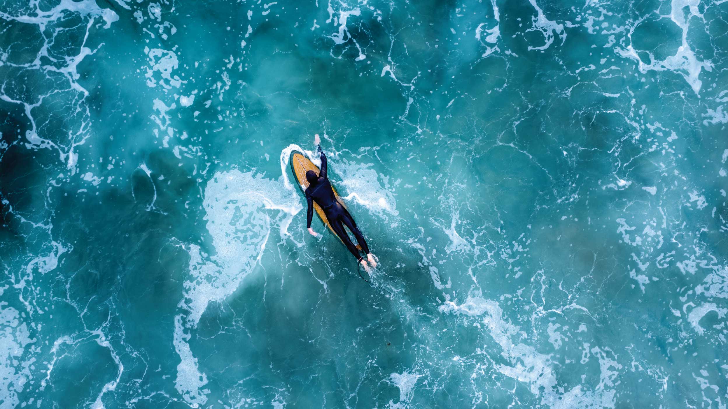 An overhead drone shot of a surfer in the wavy sea, Newport Beach, California, USA