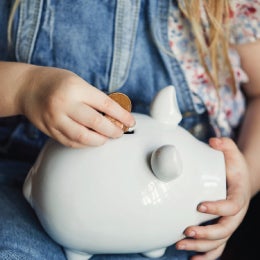 A%20person%20placing%20coins%20into%20a%20pink%20piggy%20bank,%20symbolizing%20saving%20money%20or%20financial%20planning.