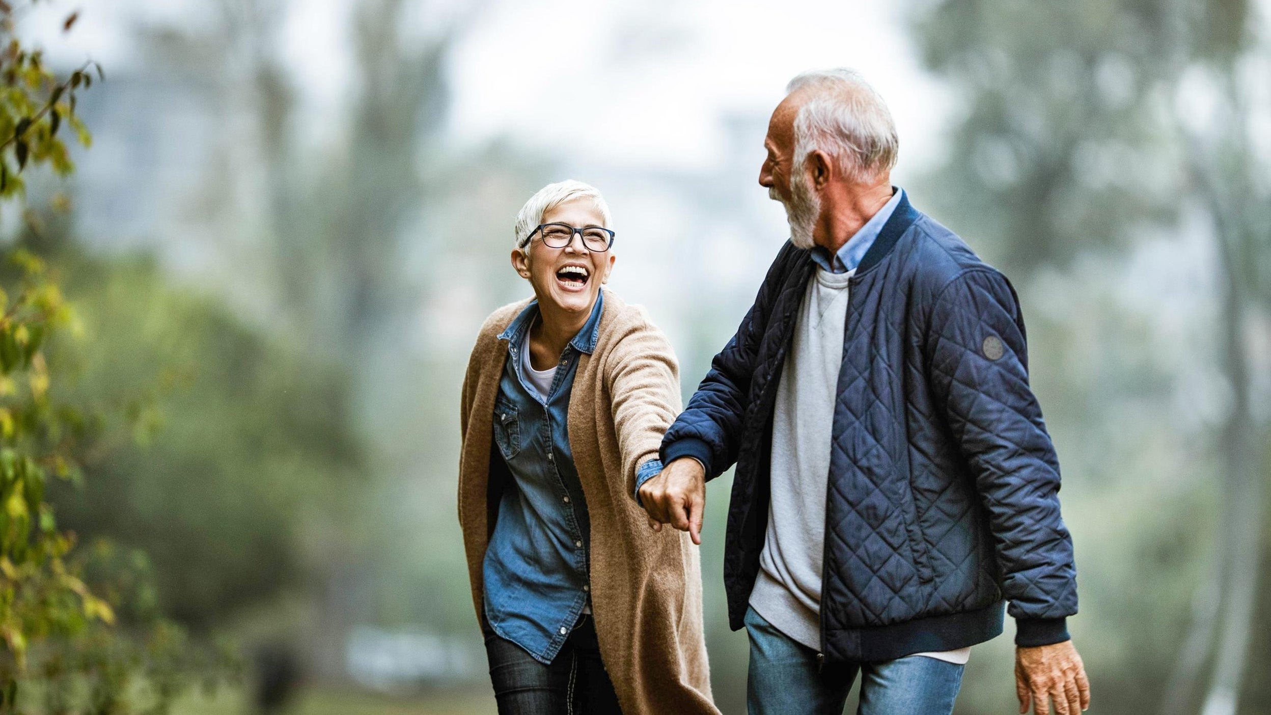 Cheerful senior couple having fun in the park. Focus is on woman.