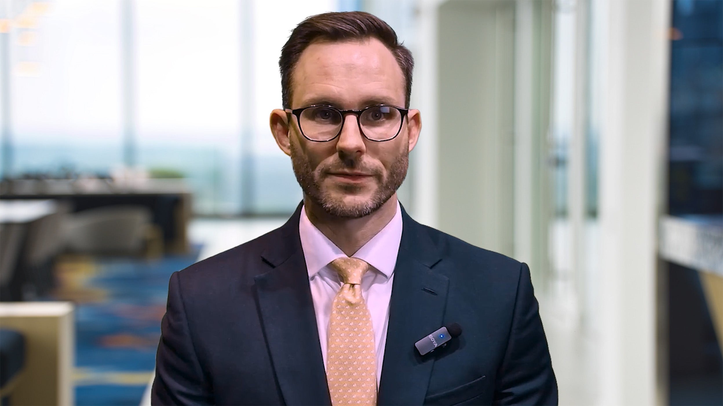 Joe Dowling speaking directly to the camera in a professional office setting.