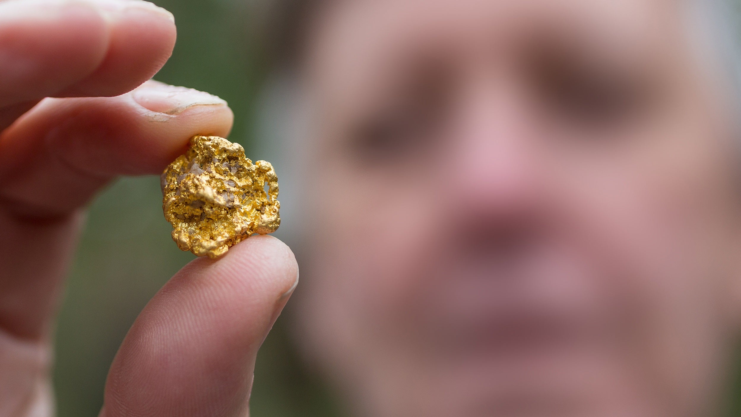 Man holding gold piece between two fingers