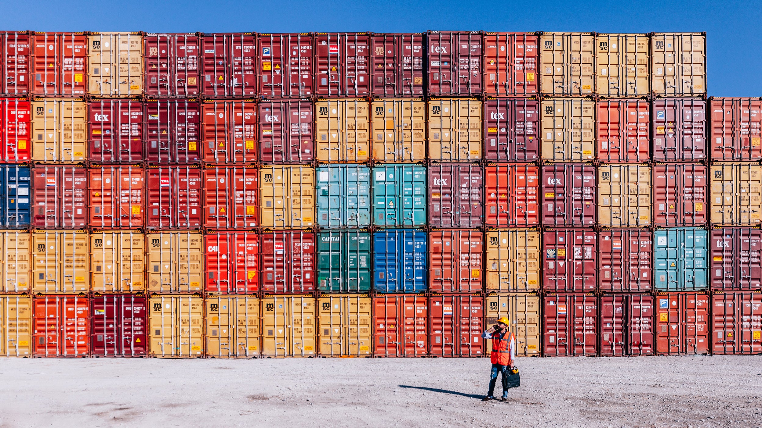 Engineer in front of colorful cargo container stacks in shipping port