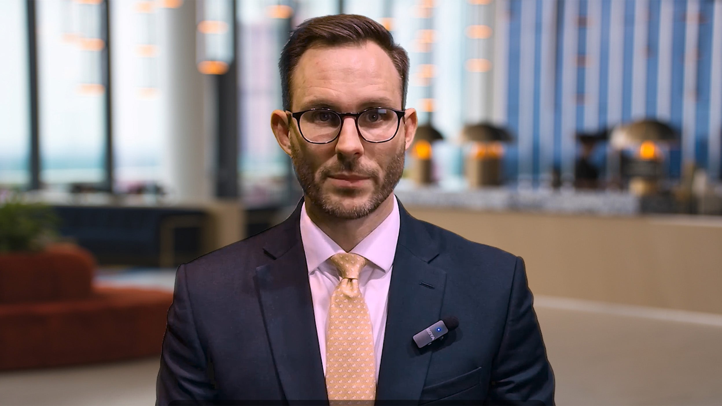 Joe Dowling speaking directly to the camera in a professional office setting.