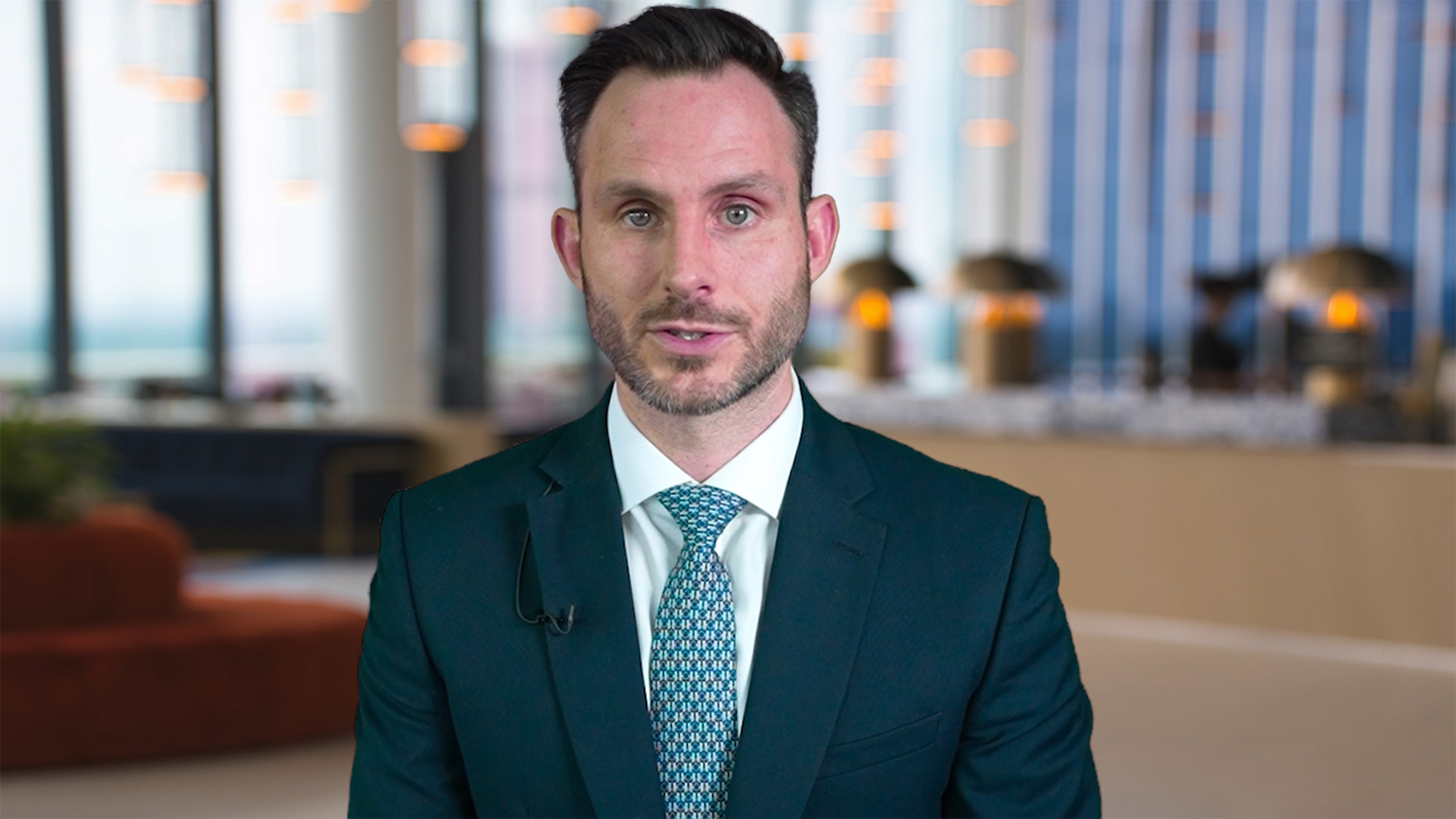 Joe Dowling speaking directly to the camera in a professional office setting.