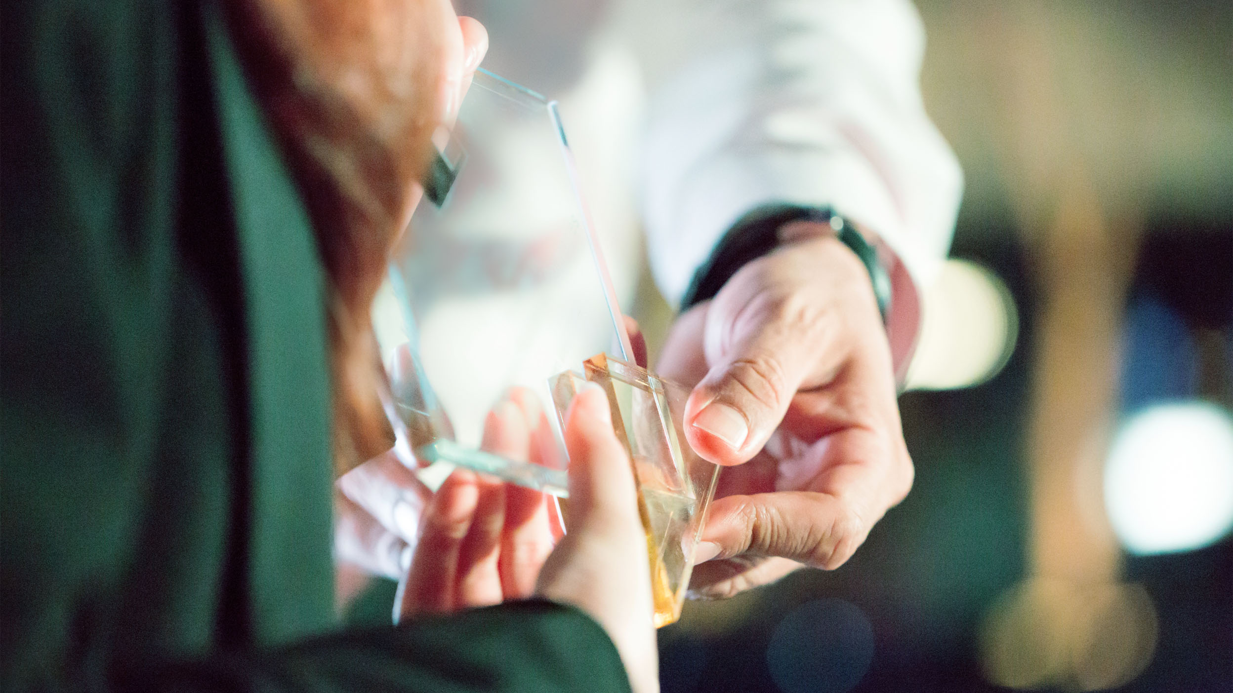 Close-up of hands exchanging a glass award