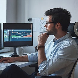 Side%20view%20of%20successful%20trader%20or%20businessman%20in%20formal%20wear%20and%20eyeglasses%20working%20with%20charts%20and%20market%20reports%20on%20computer%20screens%20in%20his%20modern%20office.