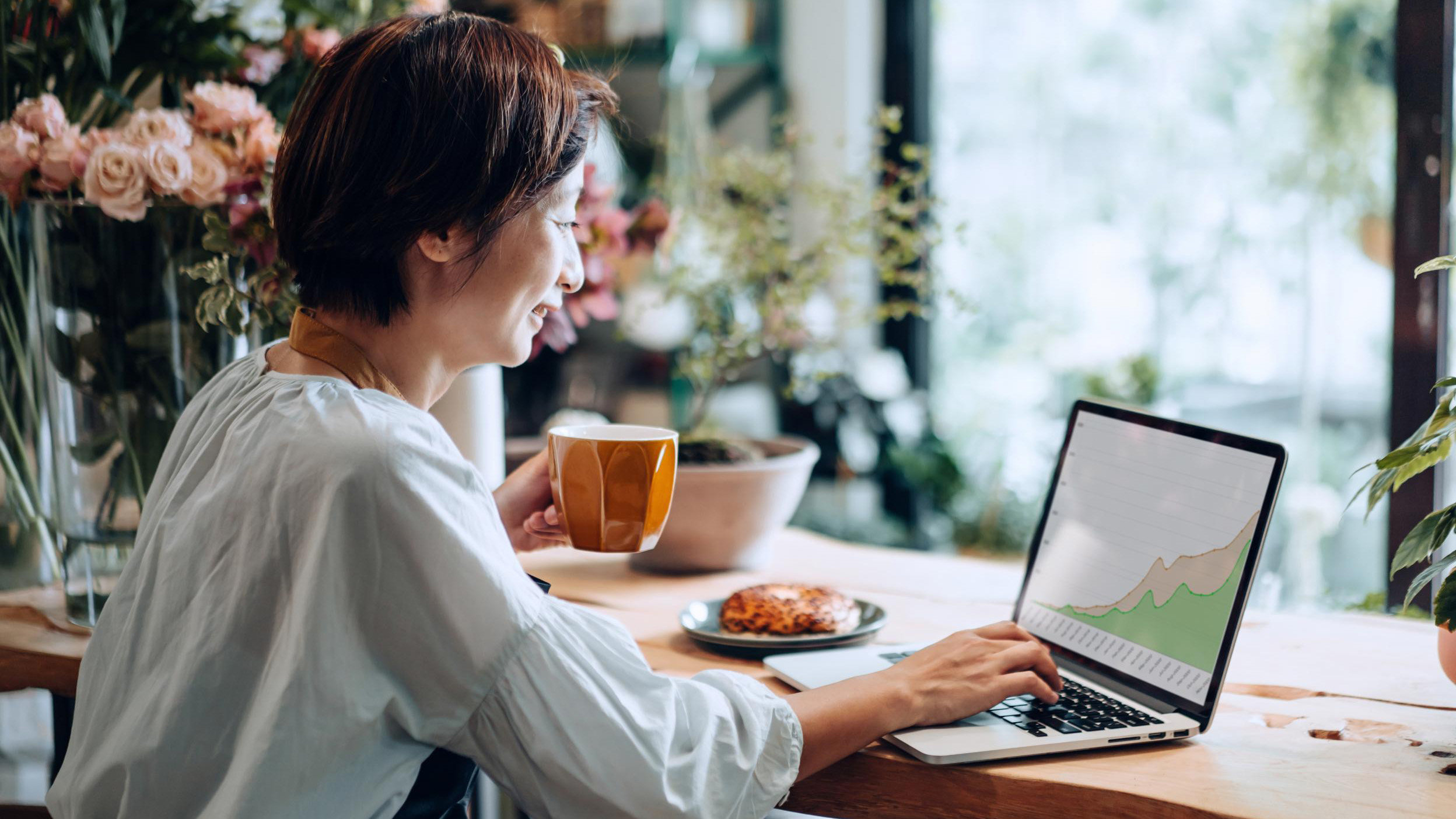 Confident smiling Asian female florist, owner of small business flower shop, analyzing business performance on laptop, reporting a growth in revenue, feeling happy and satisfied. Business growth, investment success concept