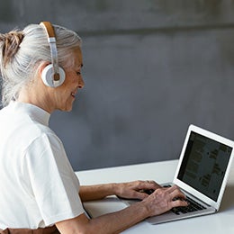 A%20woman%20with%20headphones%20sits%20at%20a%20desk,%20focused%20on%20her%20laptop%20while%20working