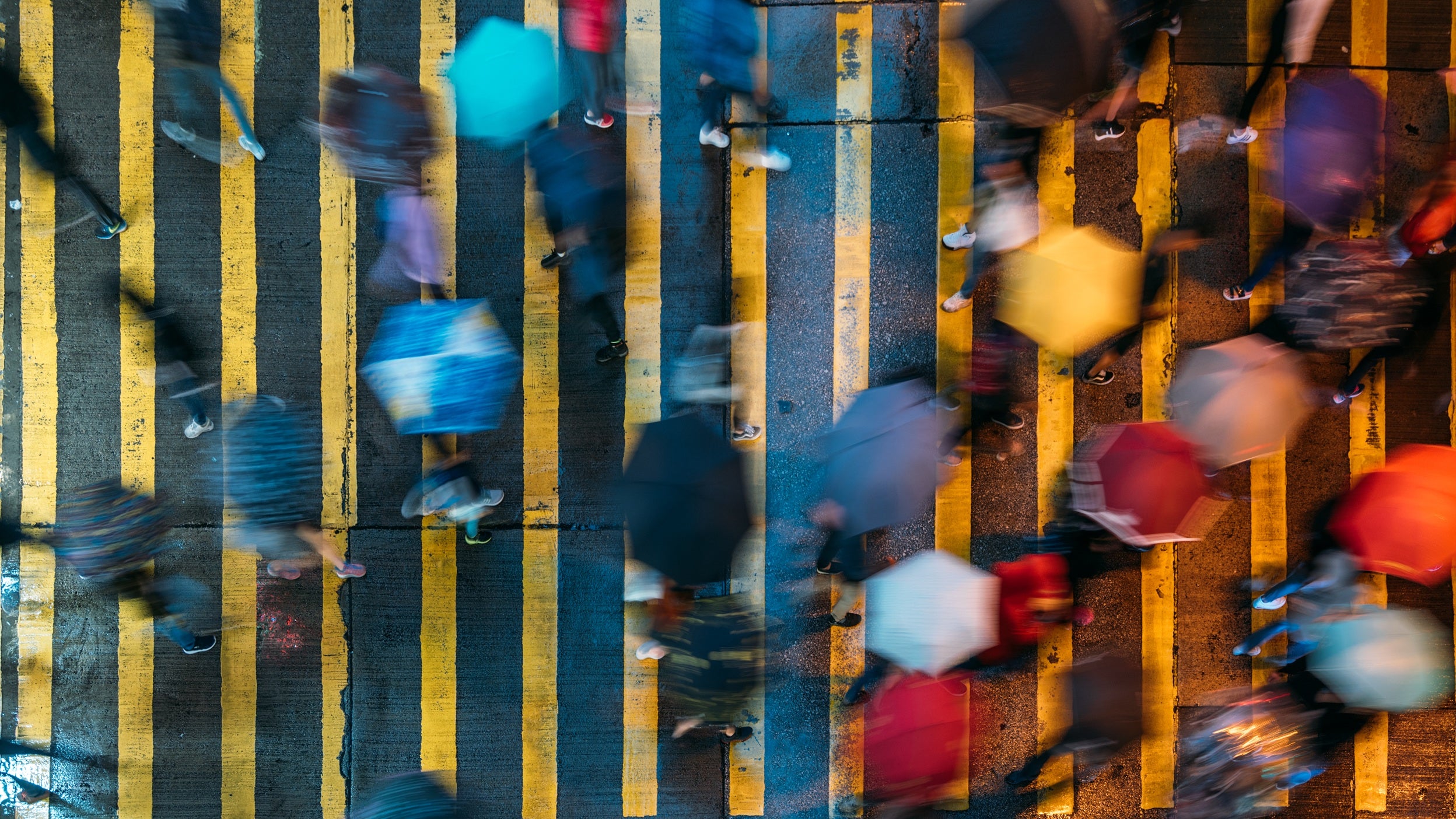 Aerial view of people on a crossing holding umbrellas