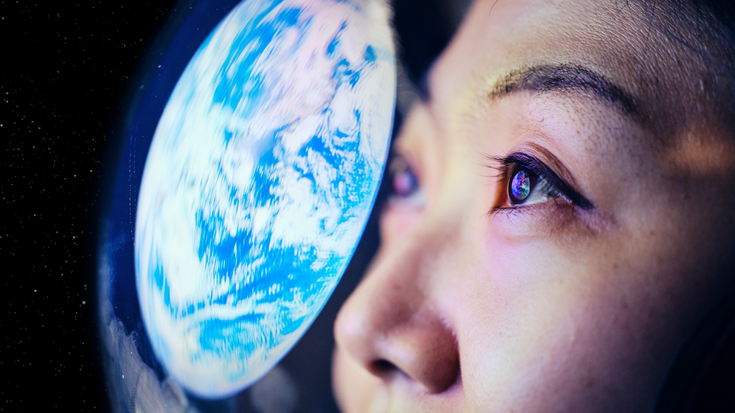 Close-up of a person’s eye reflecting an image of Earth in space.