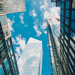 Upward%20view%20of%20modern%20glass%20skyscrapers%20against%20a%20bright%20blue%20sky%20with%20scattered%20clouds