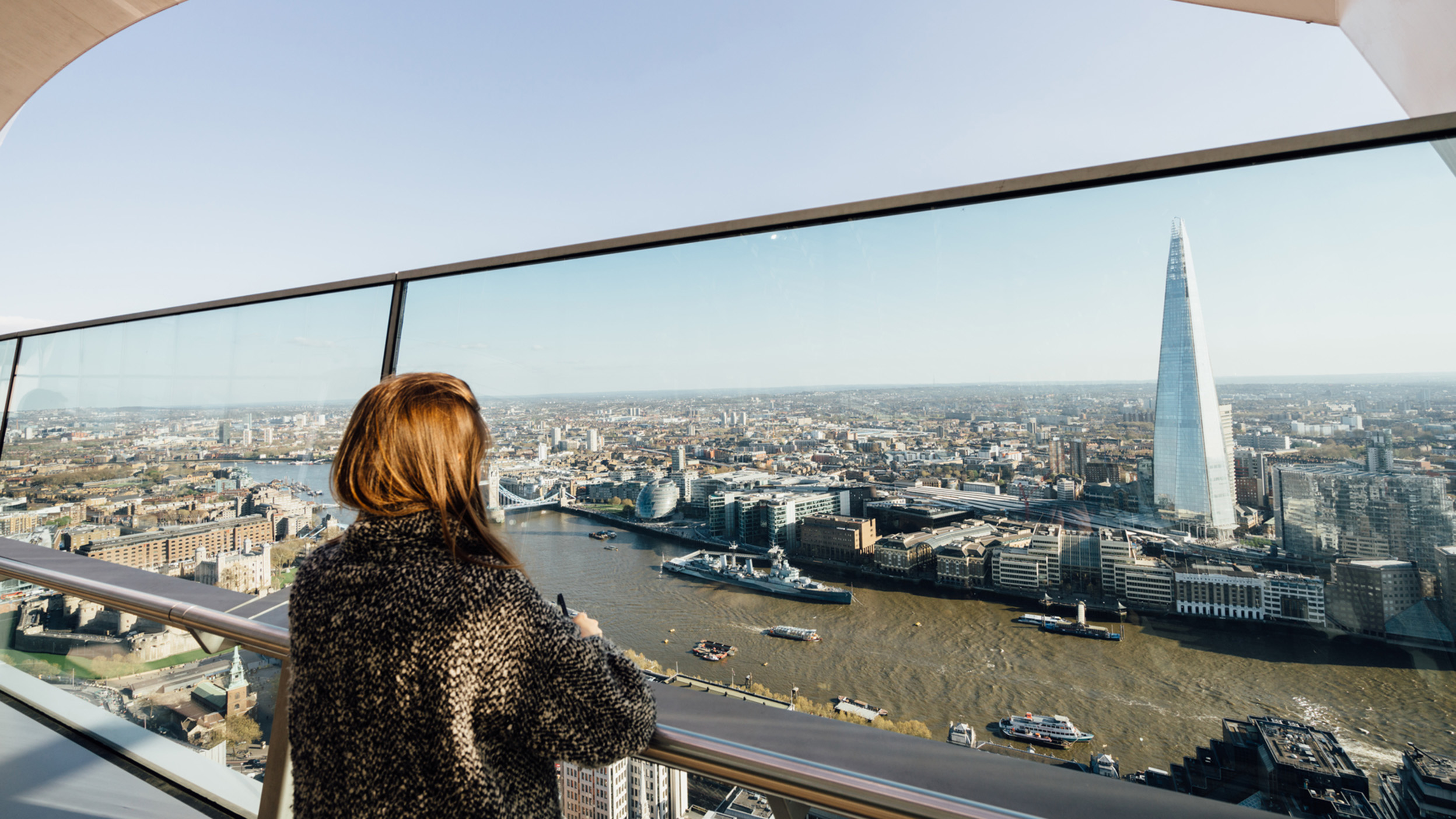 View across the River Thames and London’s financial district from a modern building, with city offices and river traffic visible.