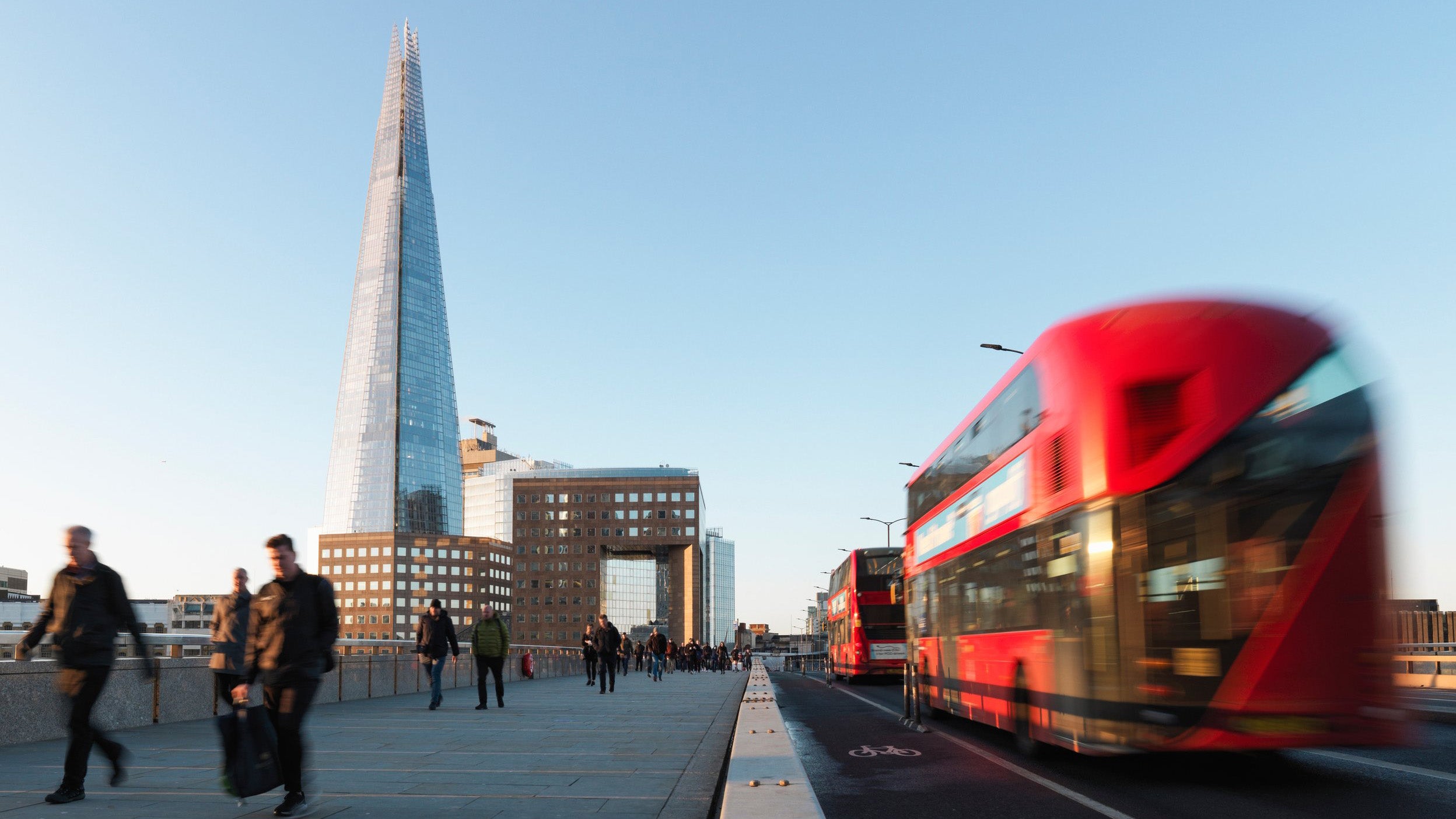 UK, London Bridge, blurred motion of business people and red busses during morning rush hour