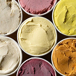 Top-down%20view%20of%20several%20tubs%20of%20ice%20cream%20in%20different%20colors%20and%20flavors%20arranged%20closely%20together.