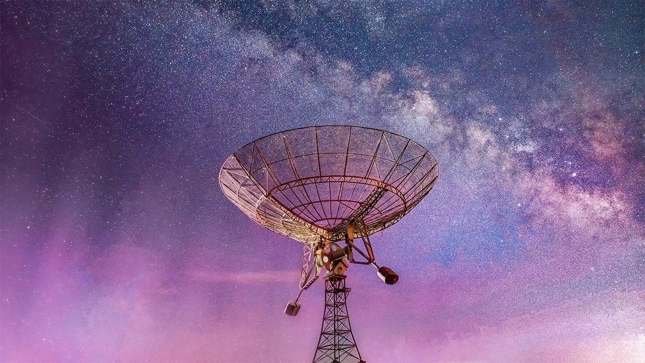 A large satellite points skyward beneath a vibrant Milky Way, symbolizing space exploration and the innovative companies advancing such technologies.