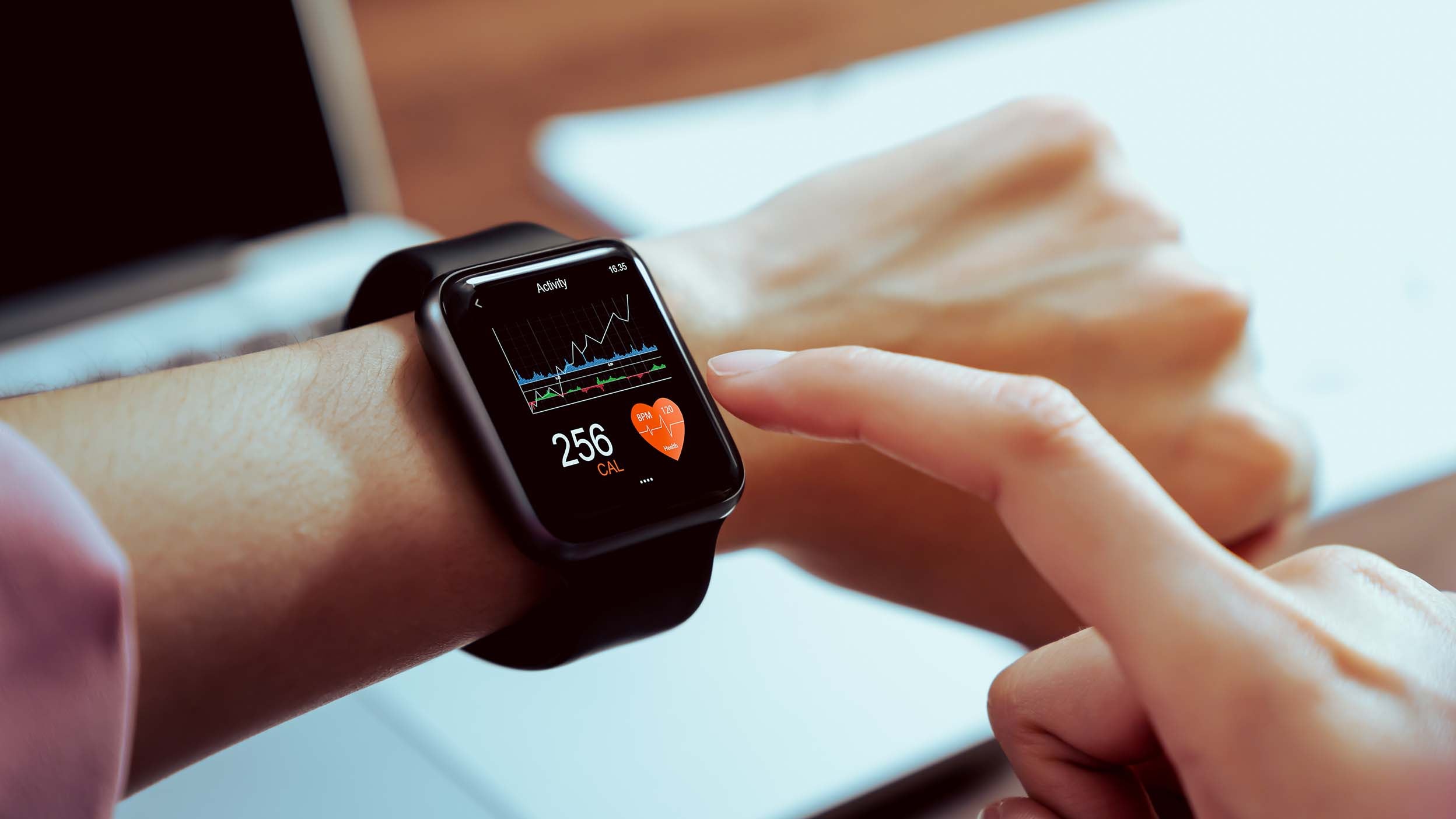 Primo piano di una mano che tocca uno smartwatch con l'app per la salute sullo schermo, gadget per uno stile di vita attivo e in forma.