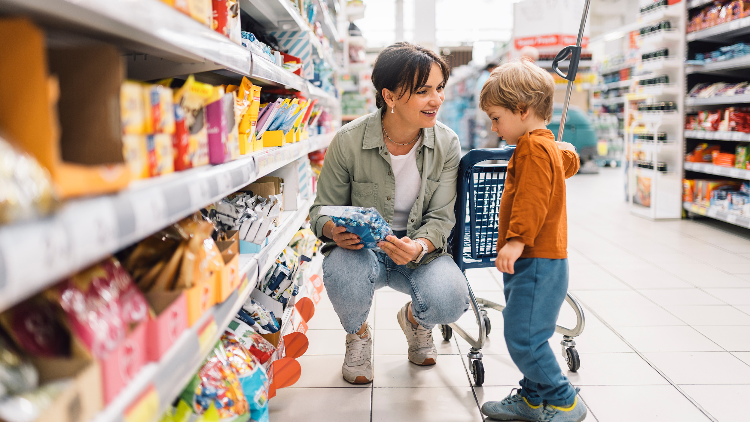 Mother shopping with her young son in a grocery store aisle