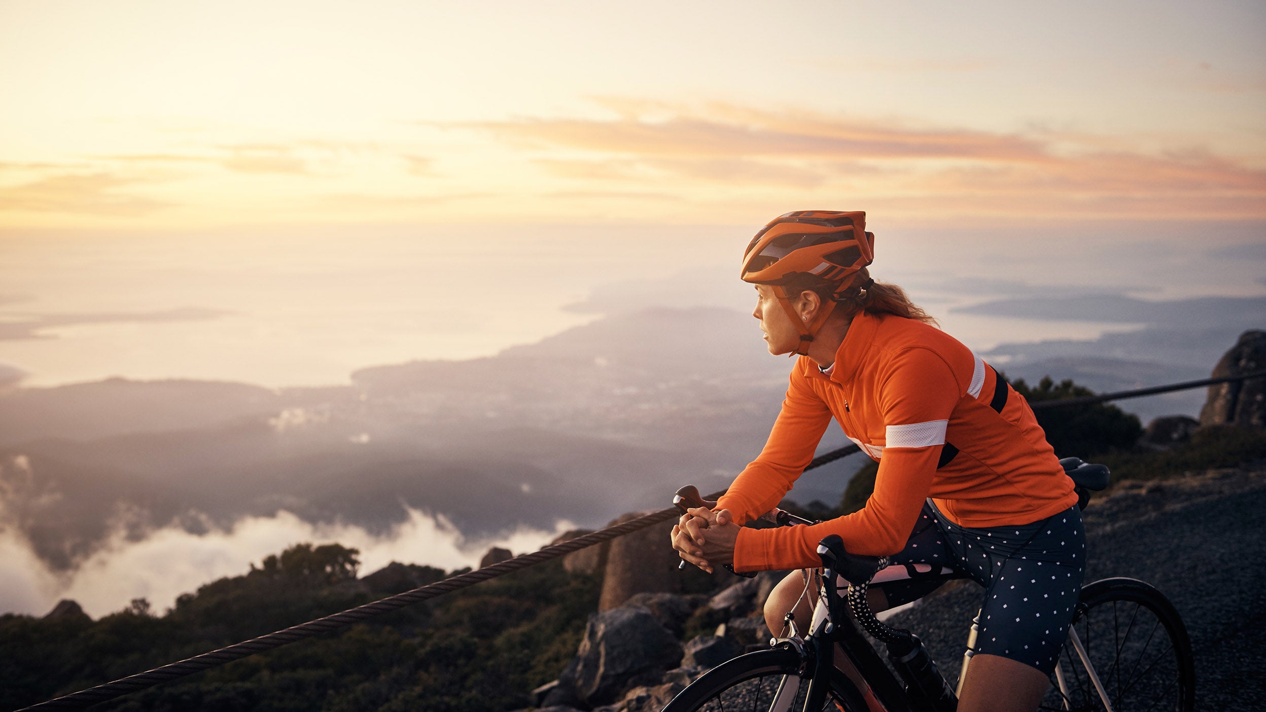 Woman on bicycle looking at sunset.