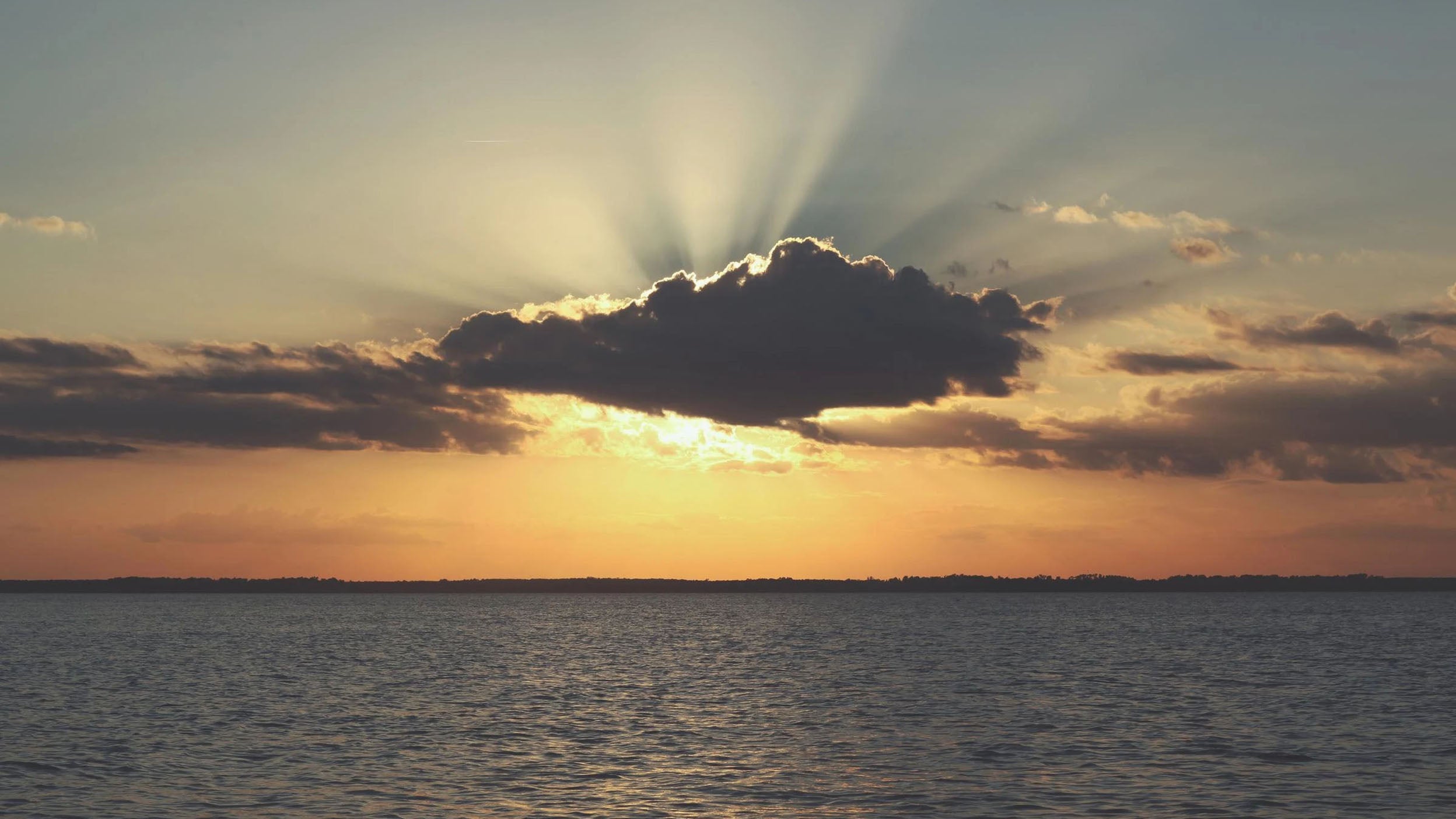 Sun covered by a cloud setting over the ocean