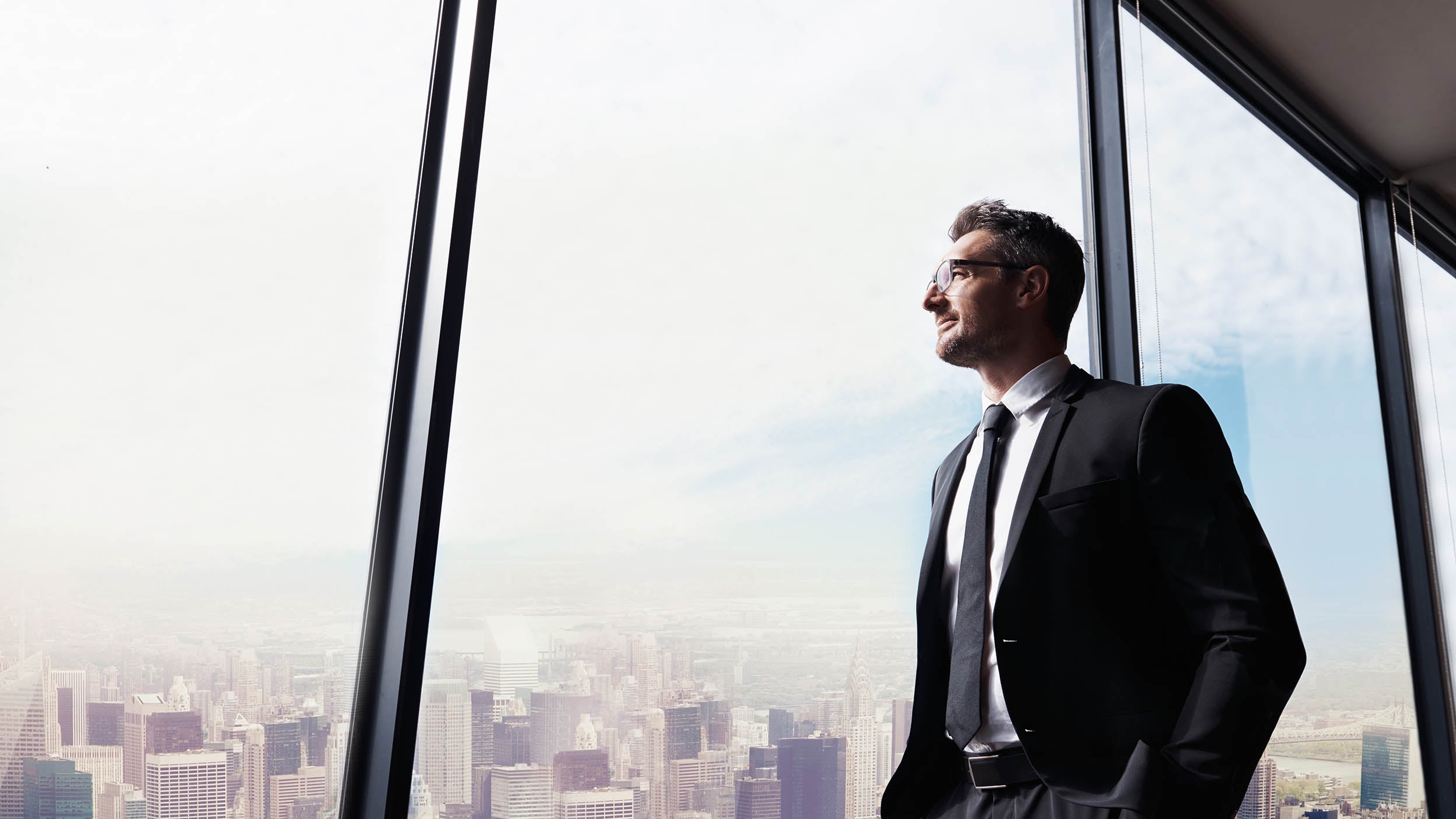 Homme qui regarde par la fenêtre de son bureau.