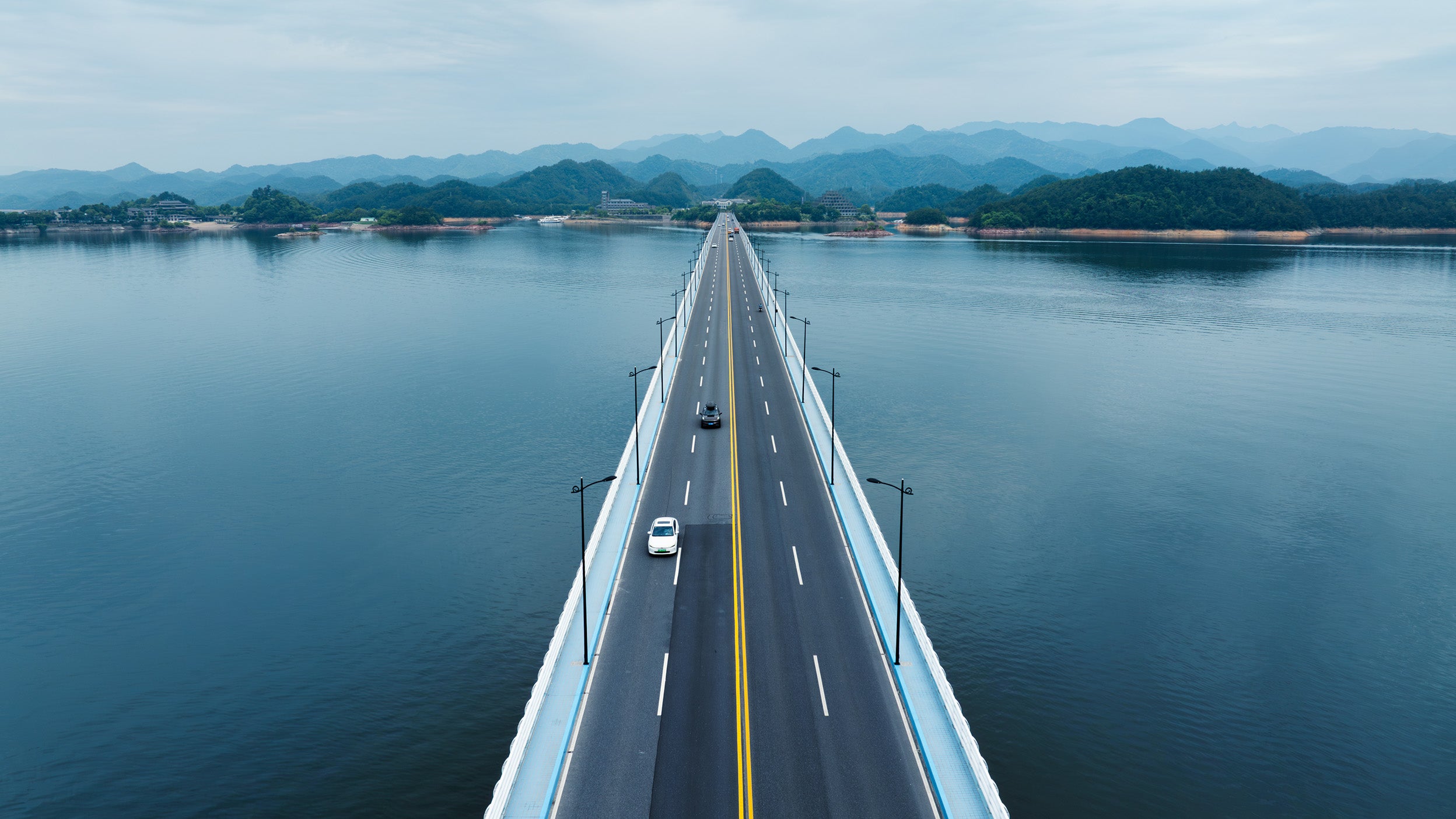 Aerial shot of a long bridge over a lake.