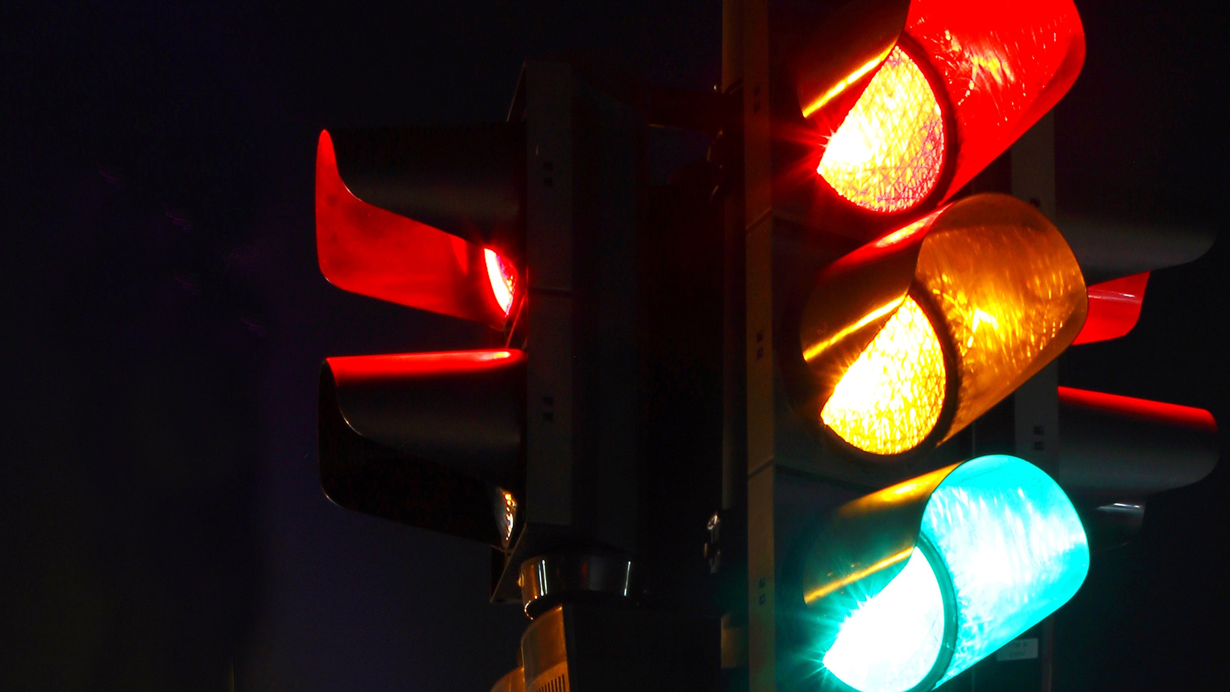 Traffic light at night, with all lights lit up.