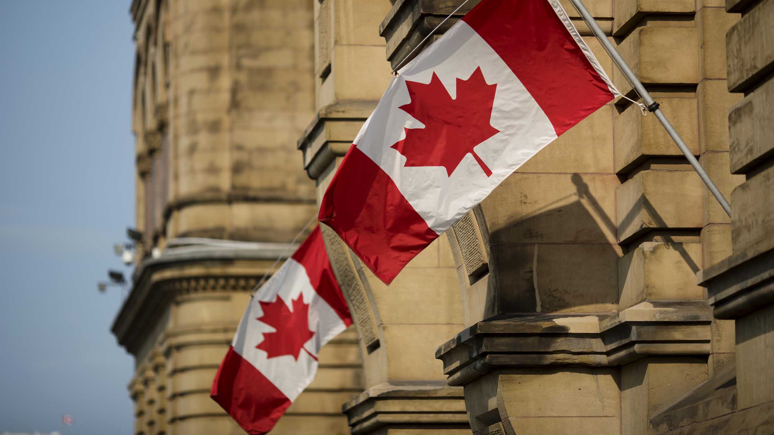 A photo of the Canadian flag waving from a building.