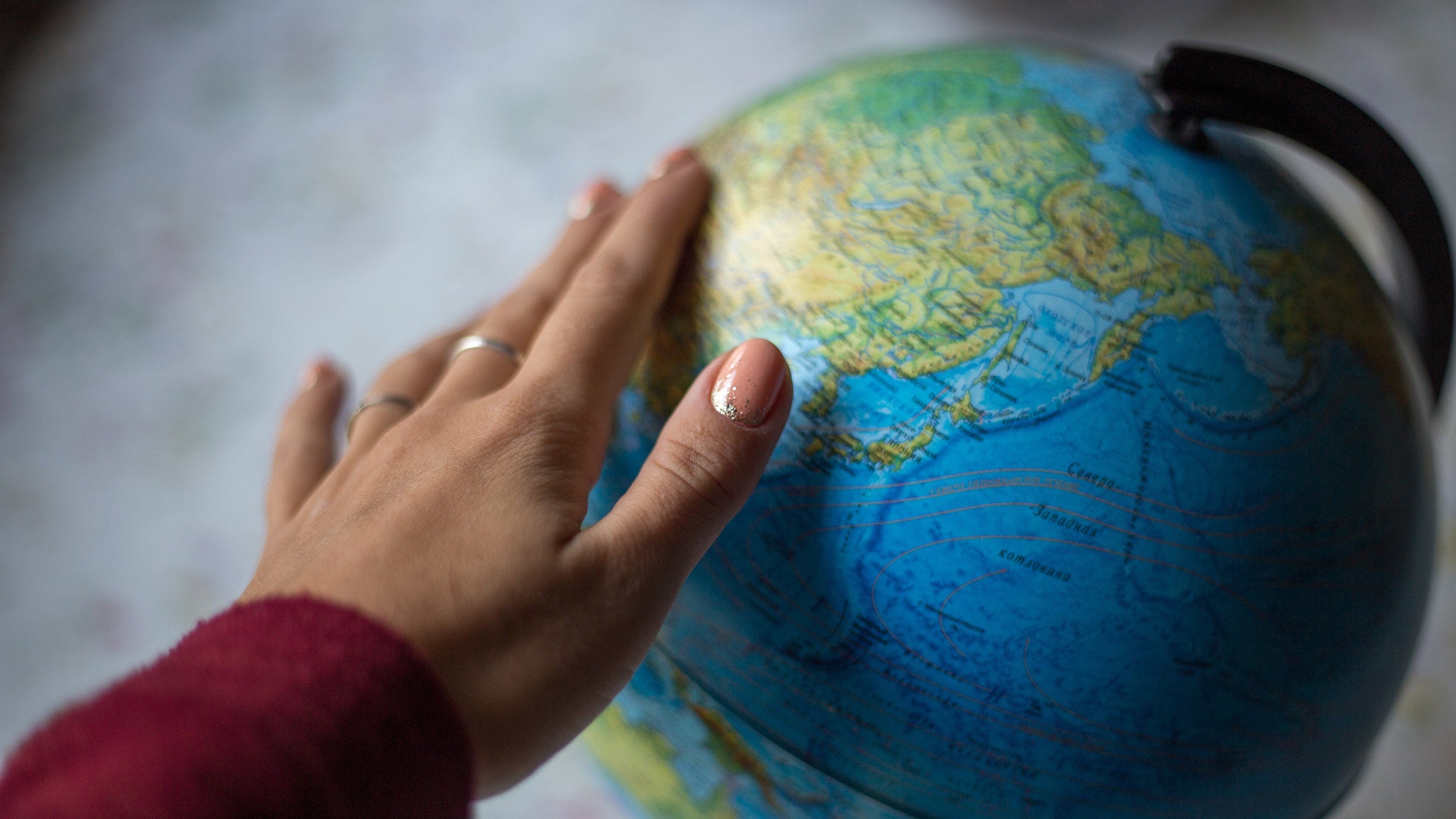 A person’s hand turns a globe.