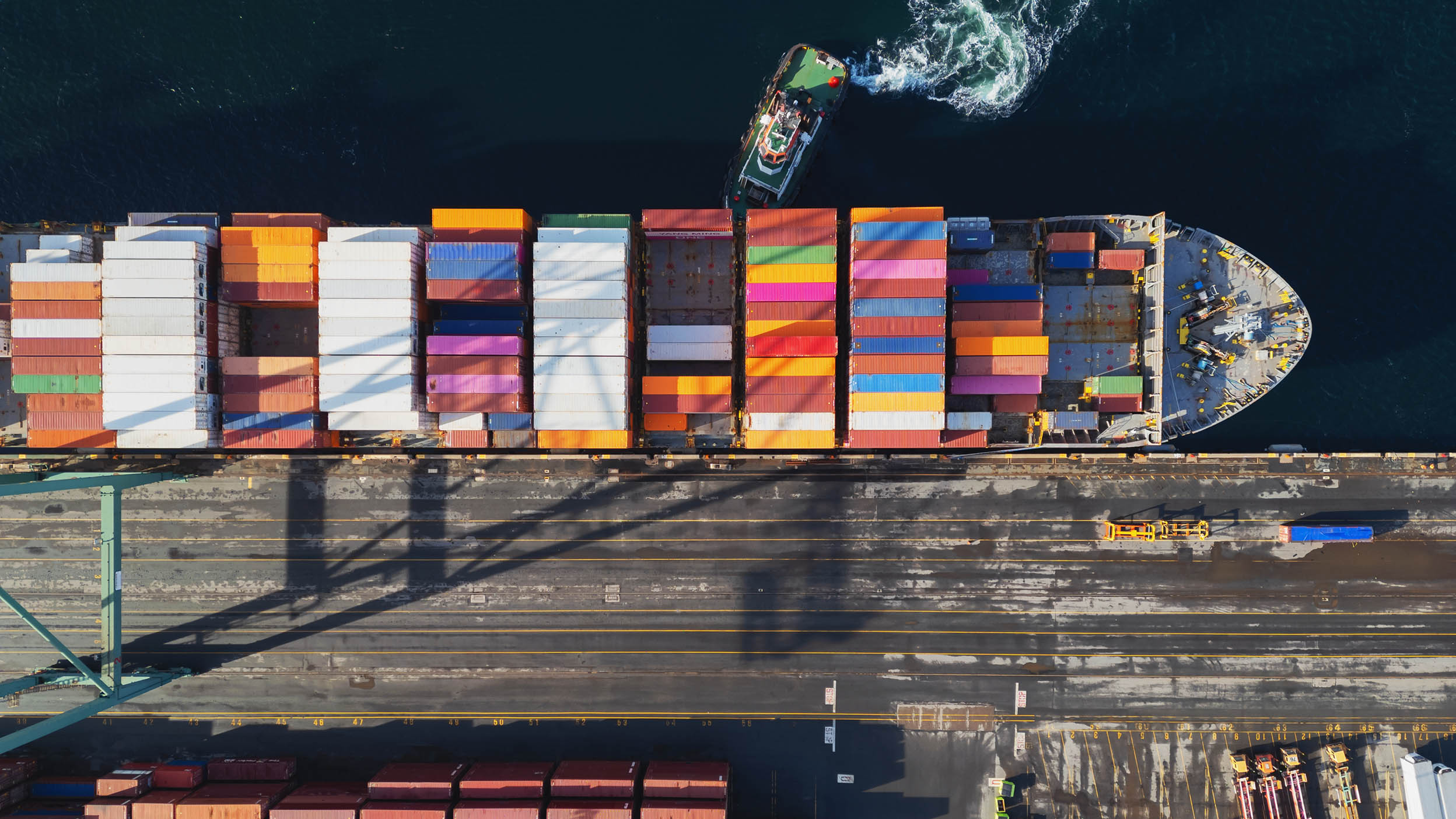 Aerial view of tugboats helping to dock a container ship